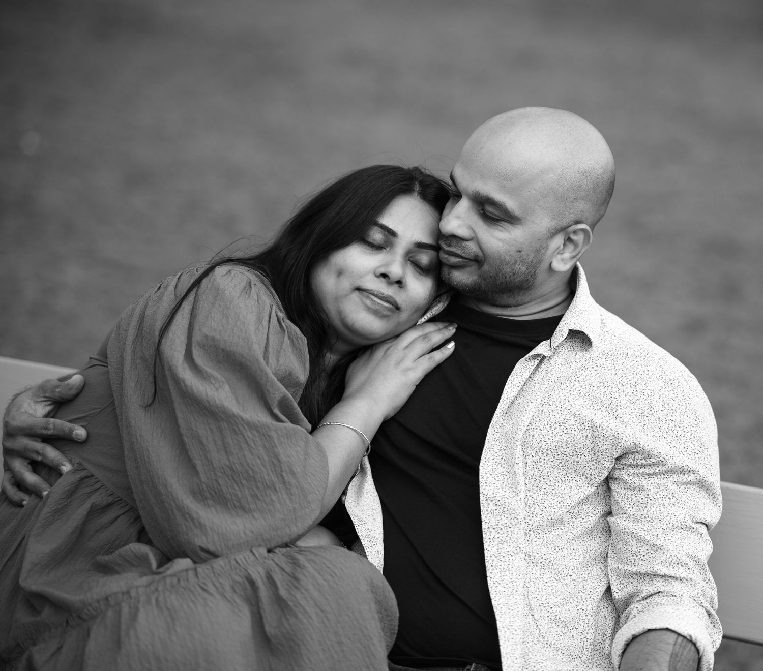Romantic black and white photo series of a couple sharing intimate moments on a park bench at sunset.