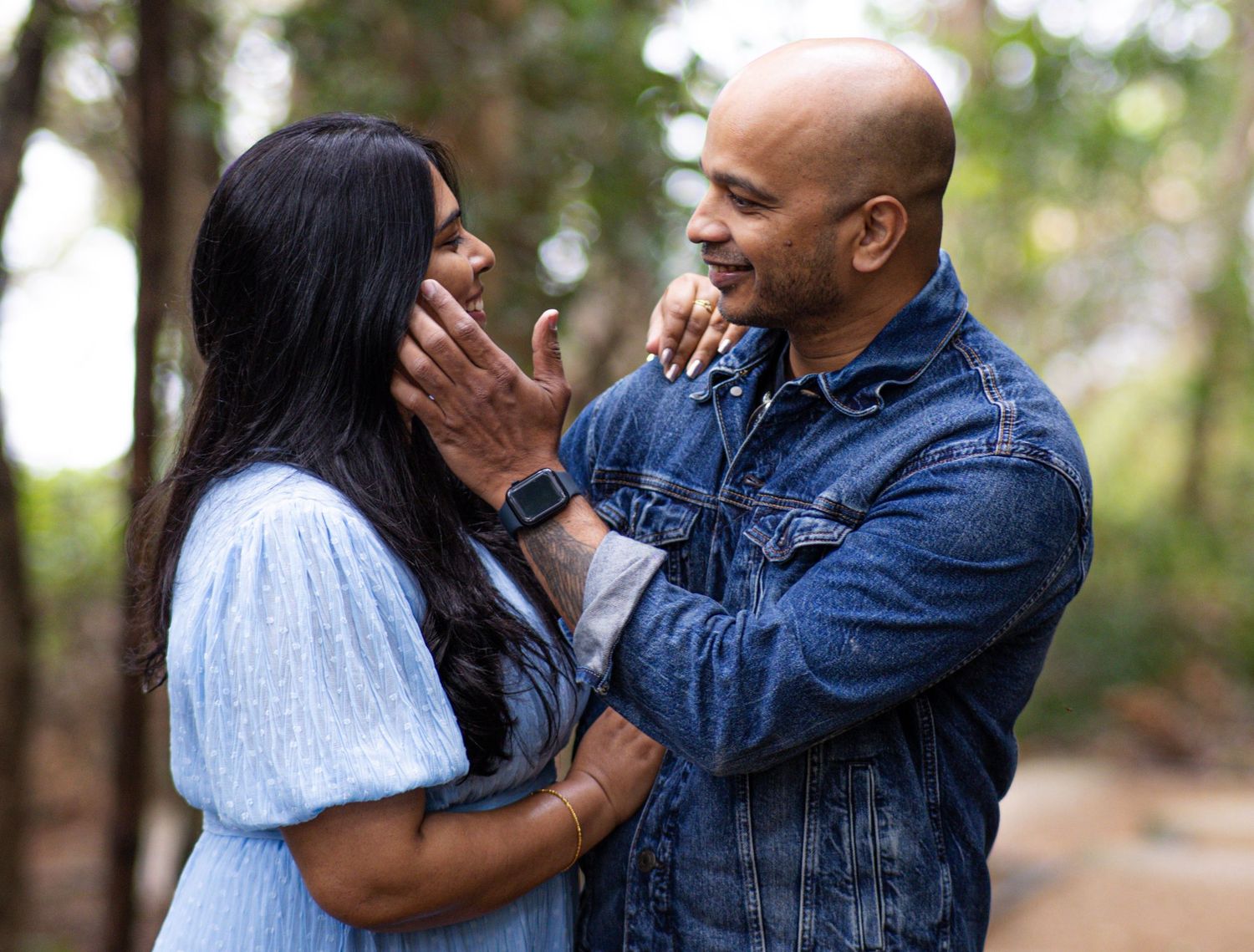 Candid moments between a couple showing playful affection in a wooded outdoor photoshoot.