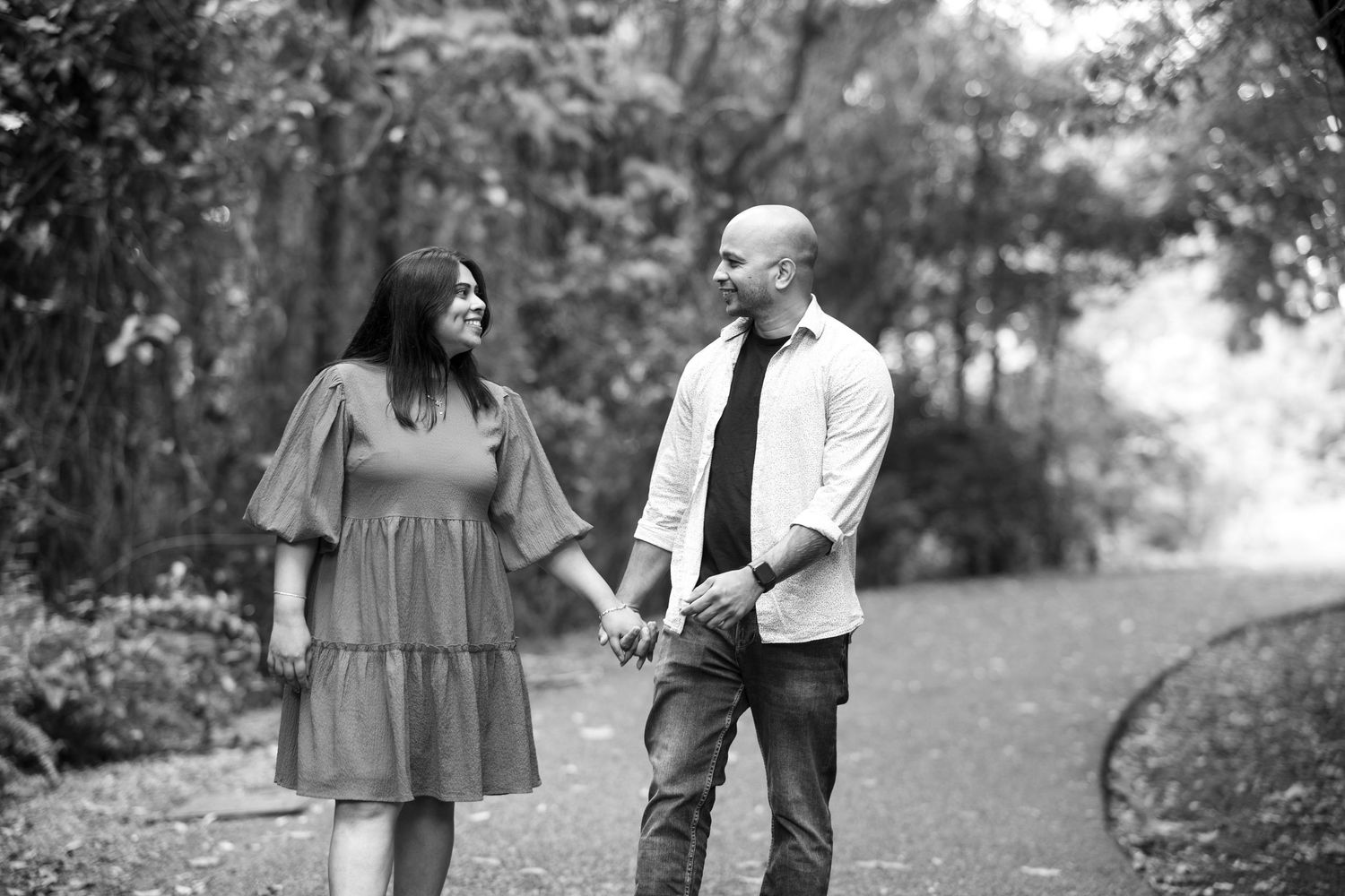 A couple walks together through a park setting during a black and white photography session.
