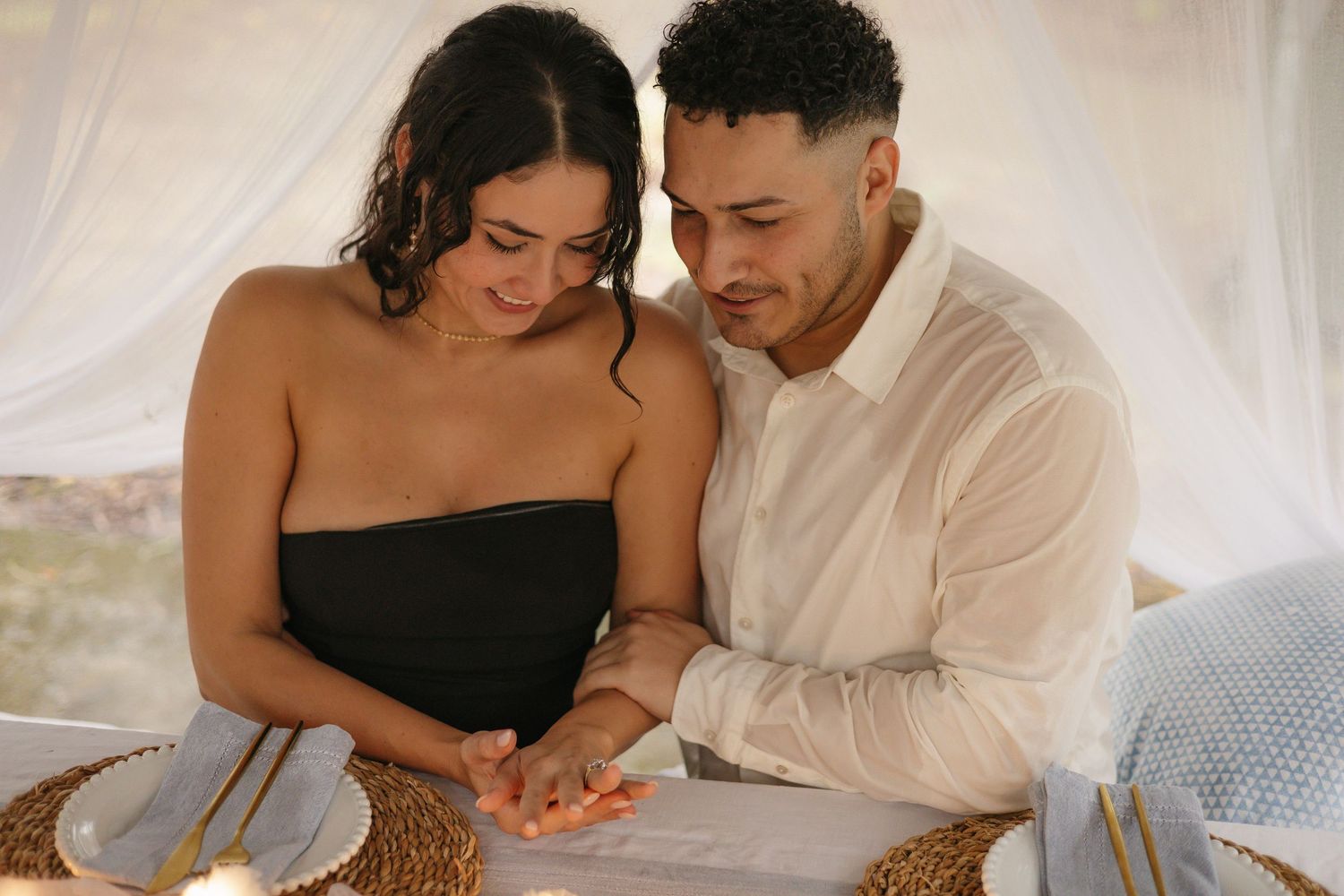 Intimate couple's photoshoot with dreamy white fabric backdrop and warm lighting.