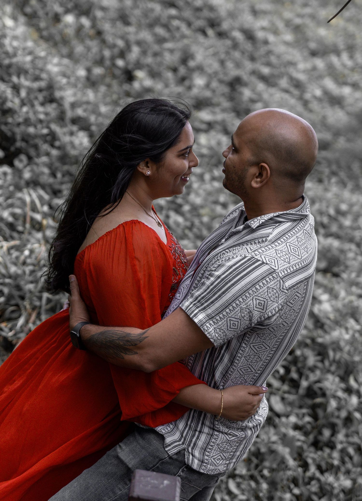 Happy couple sharing an intimate moment in selective color photo with red dress.