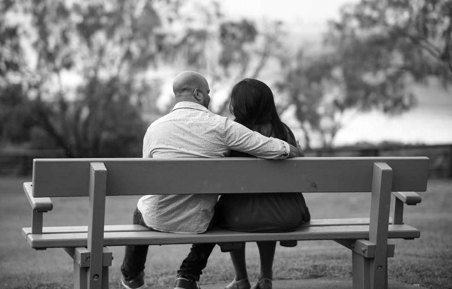 Romantic couple sitting together on wooden benches in a peaceful outdoor setting.