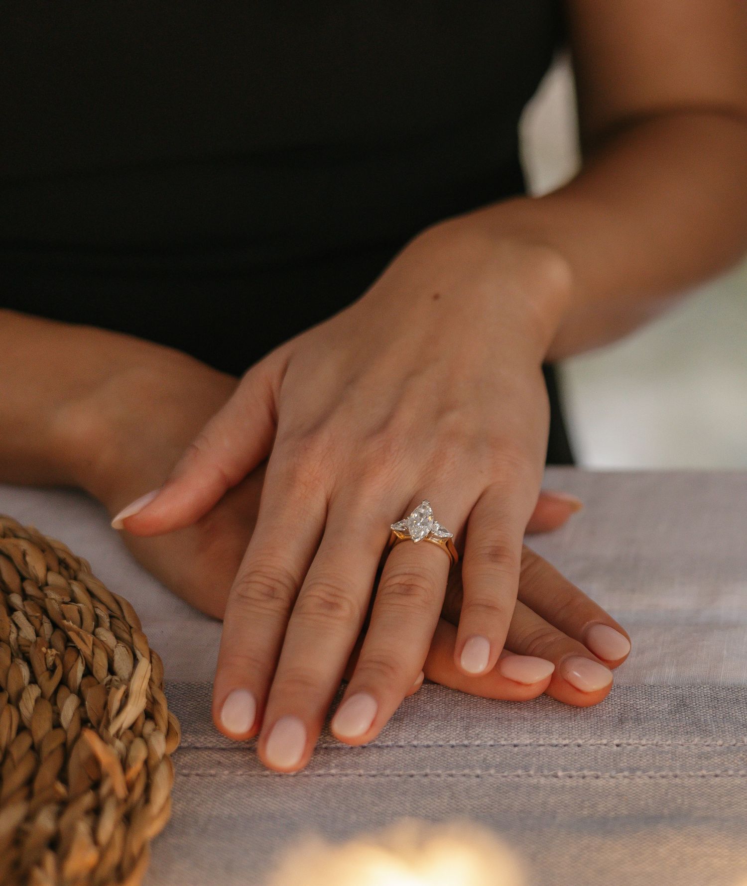 Close-up of hands showing an elegant engagement ring against a textured surface.