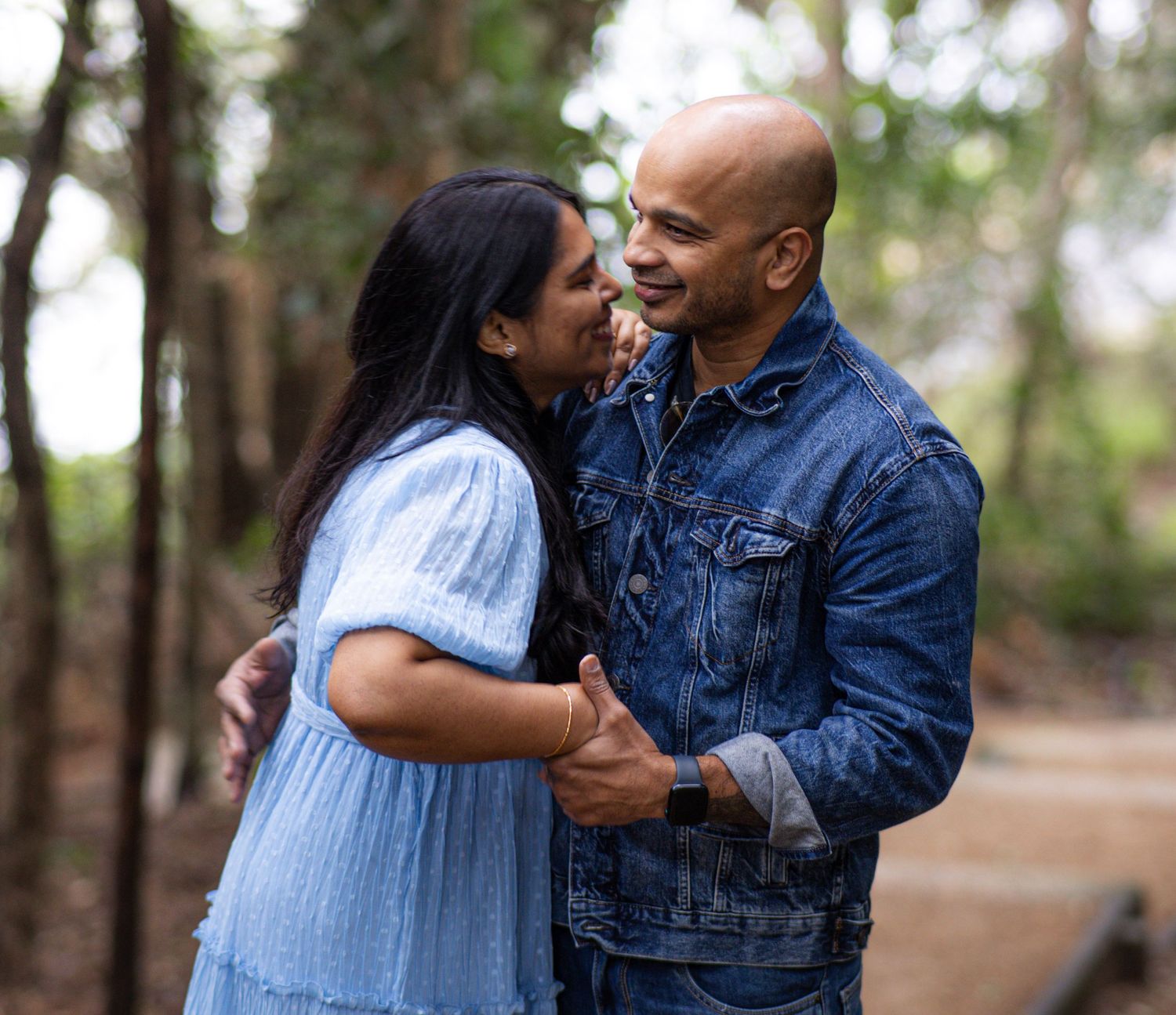Sweet outdoor couple photos showing tender moments in a forest setting with coordinated casual outfits.