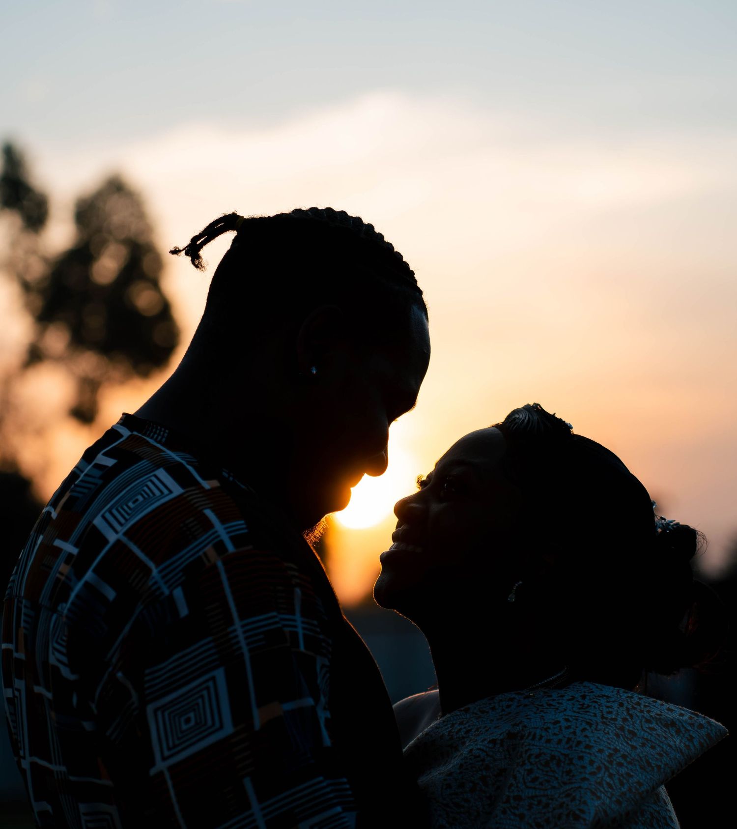 Dramatic silhouette portrait of couple against warm sunset sky.