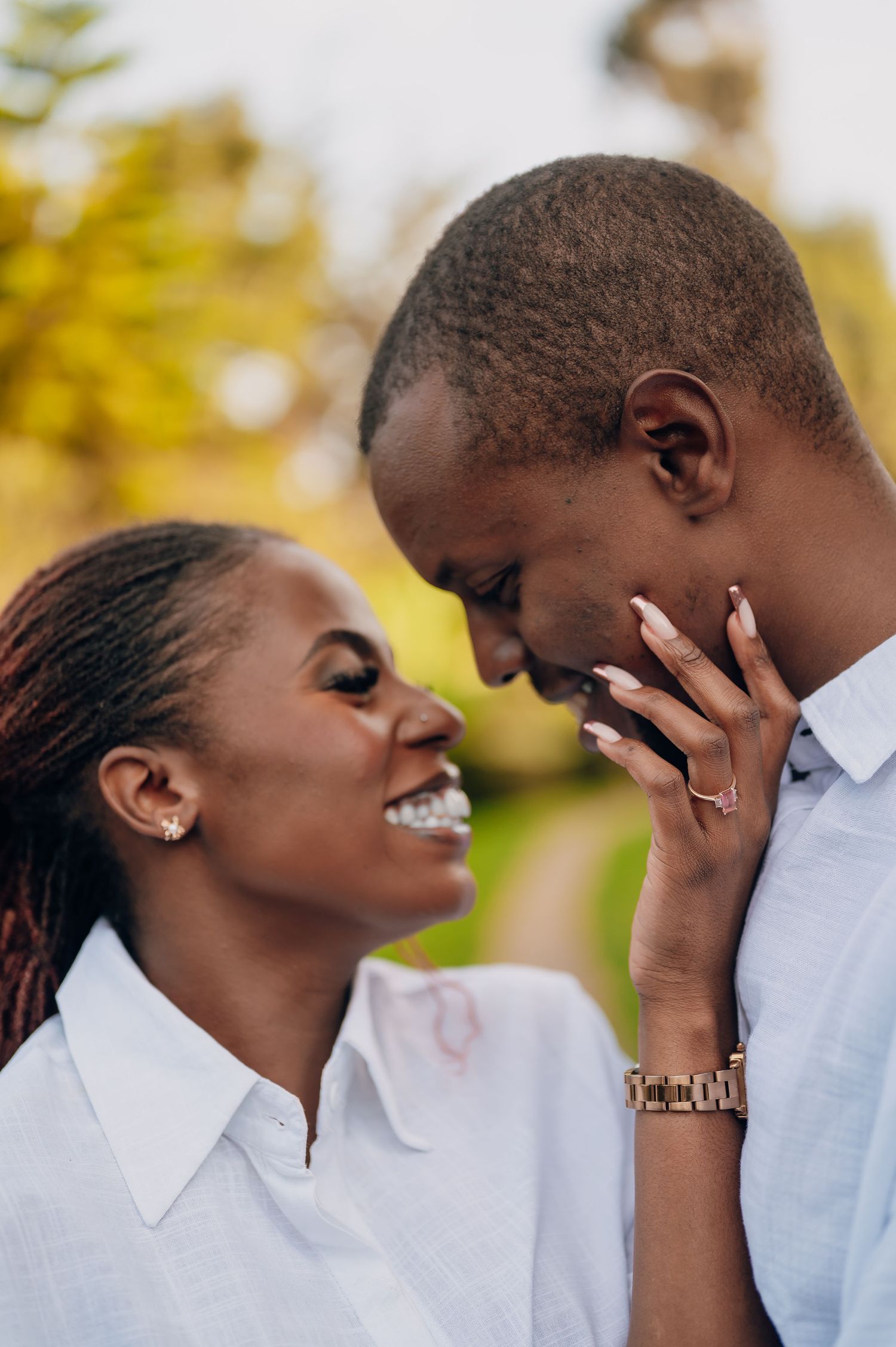 Close up of couple sharing joyful laughter against natural outdoor backdrop.