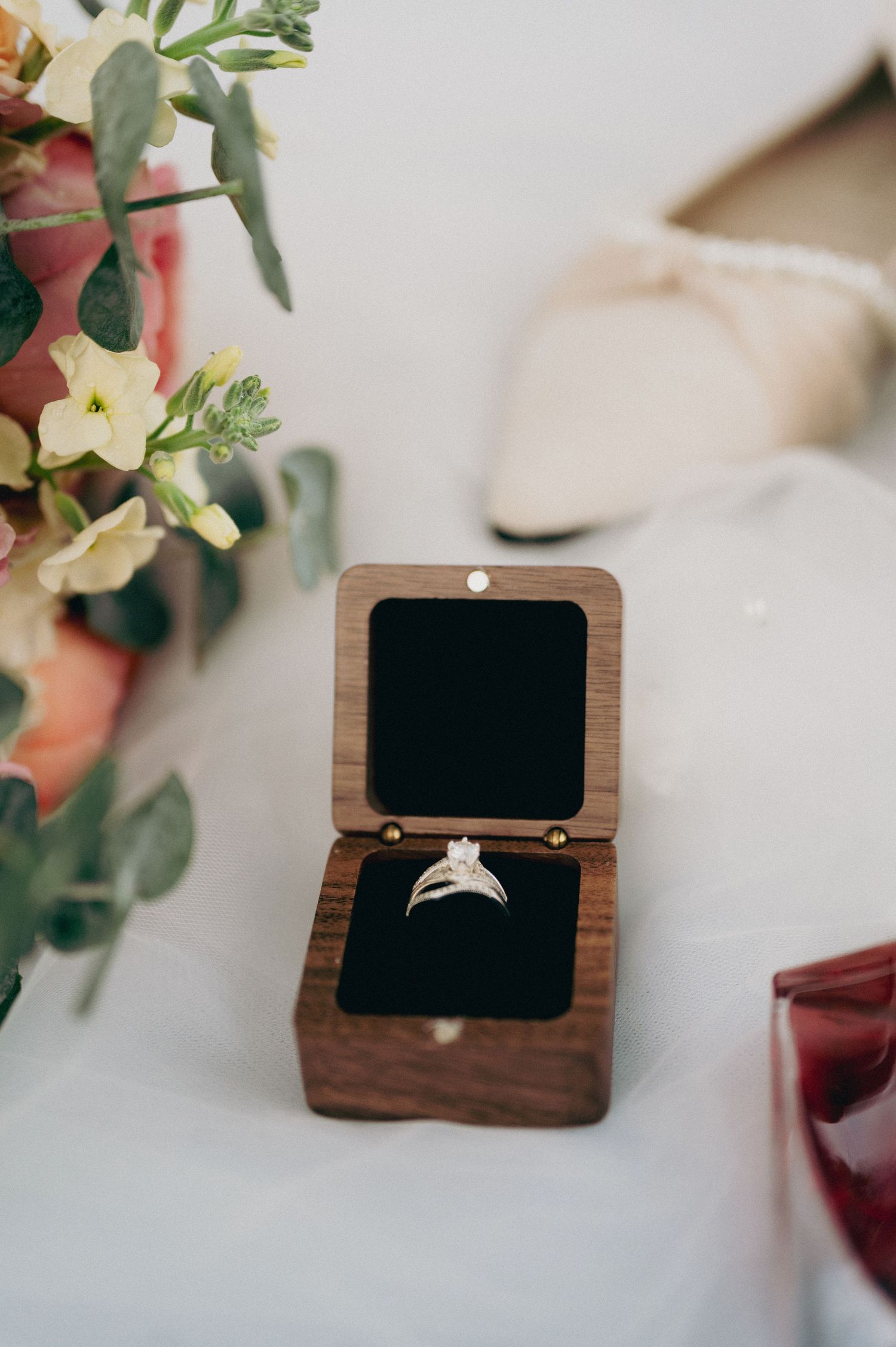 Elegant diamond engagement ring displayed in a small wooden ring box with floral decorations.
