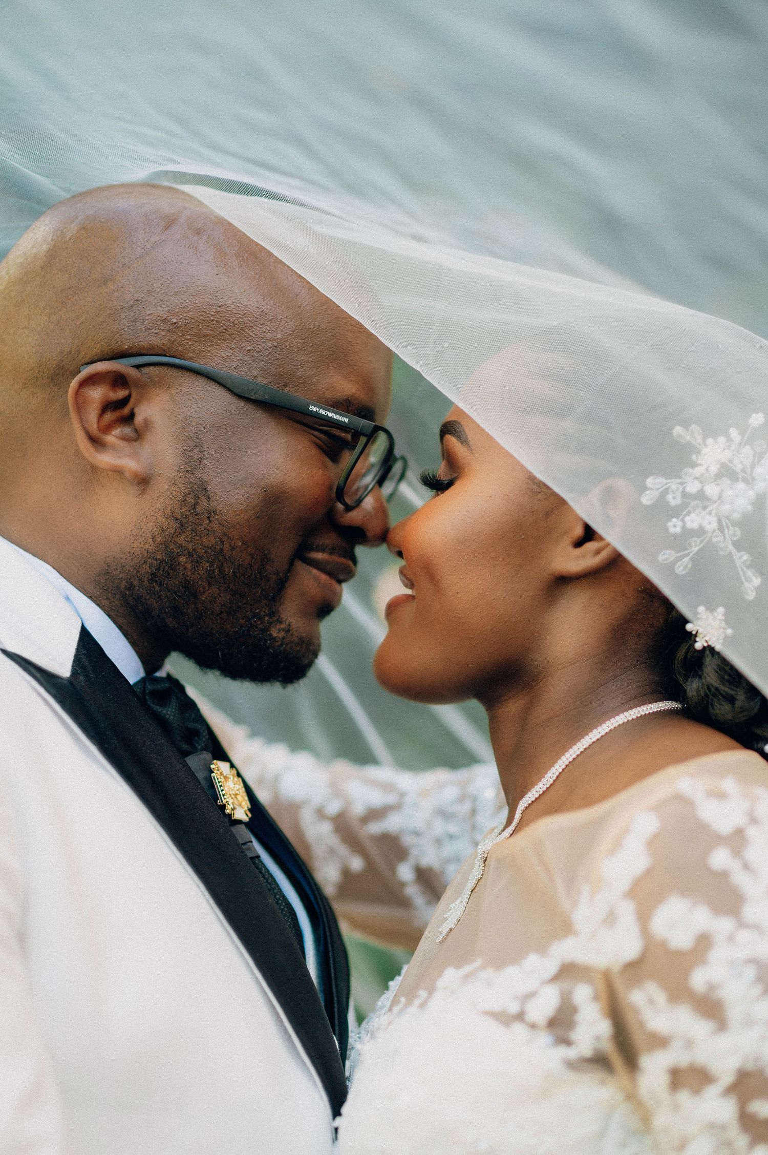 Close-up of romantic wedding couple sharing intimate moment under veil.