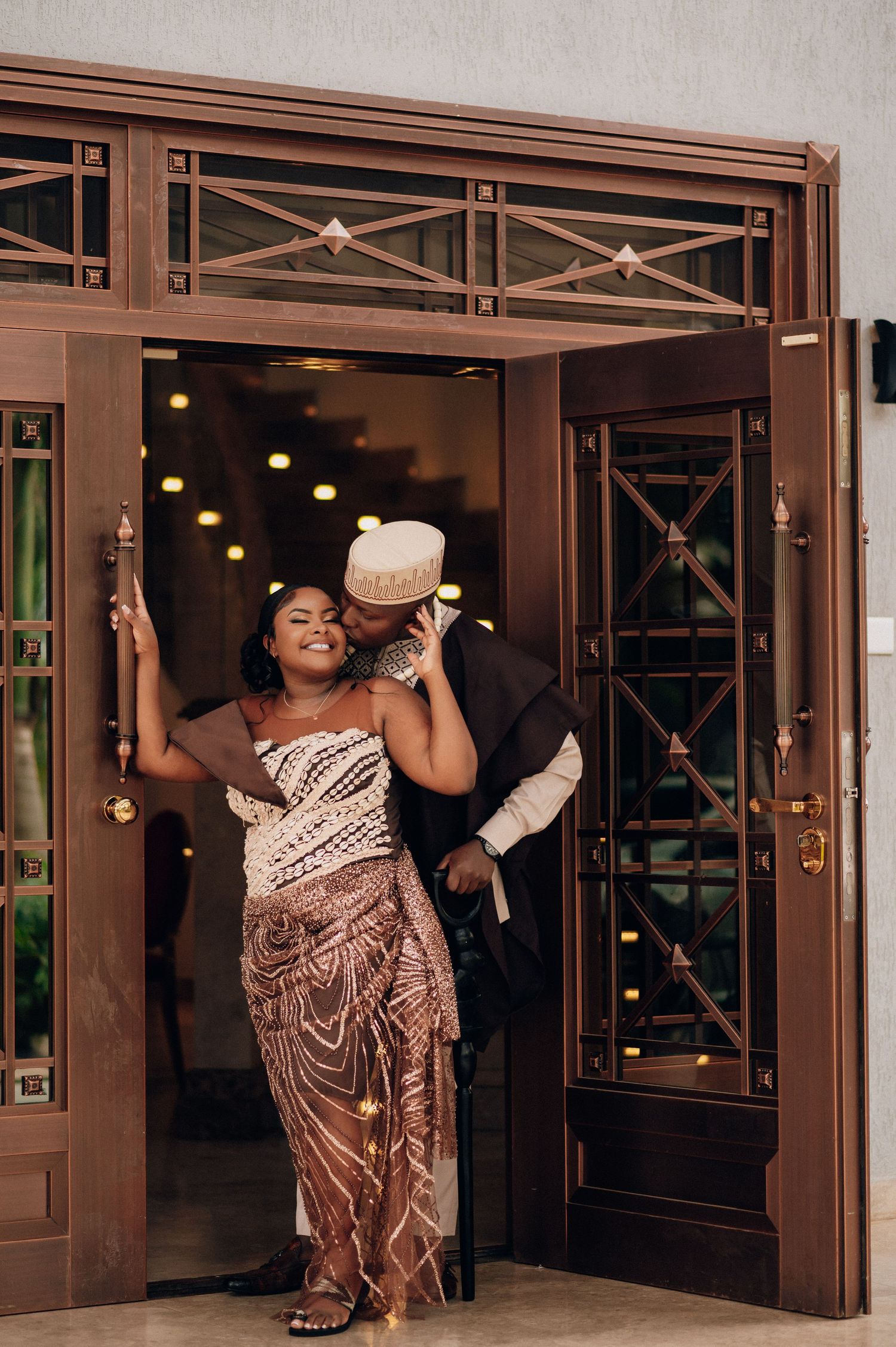 A couple dancing in formal attire at an elegant venue with decorative bronze doors.