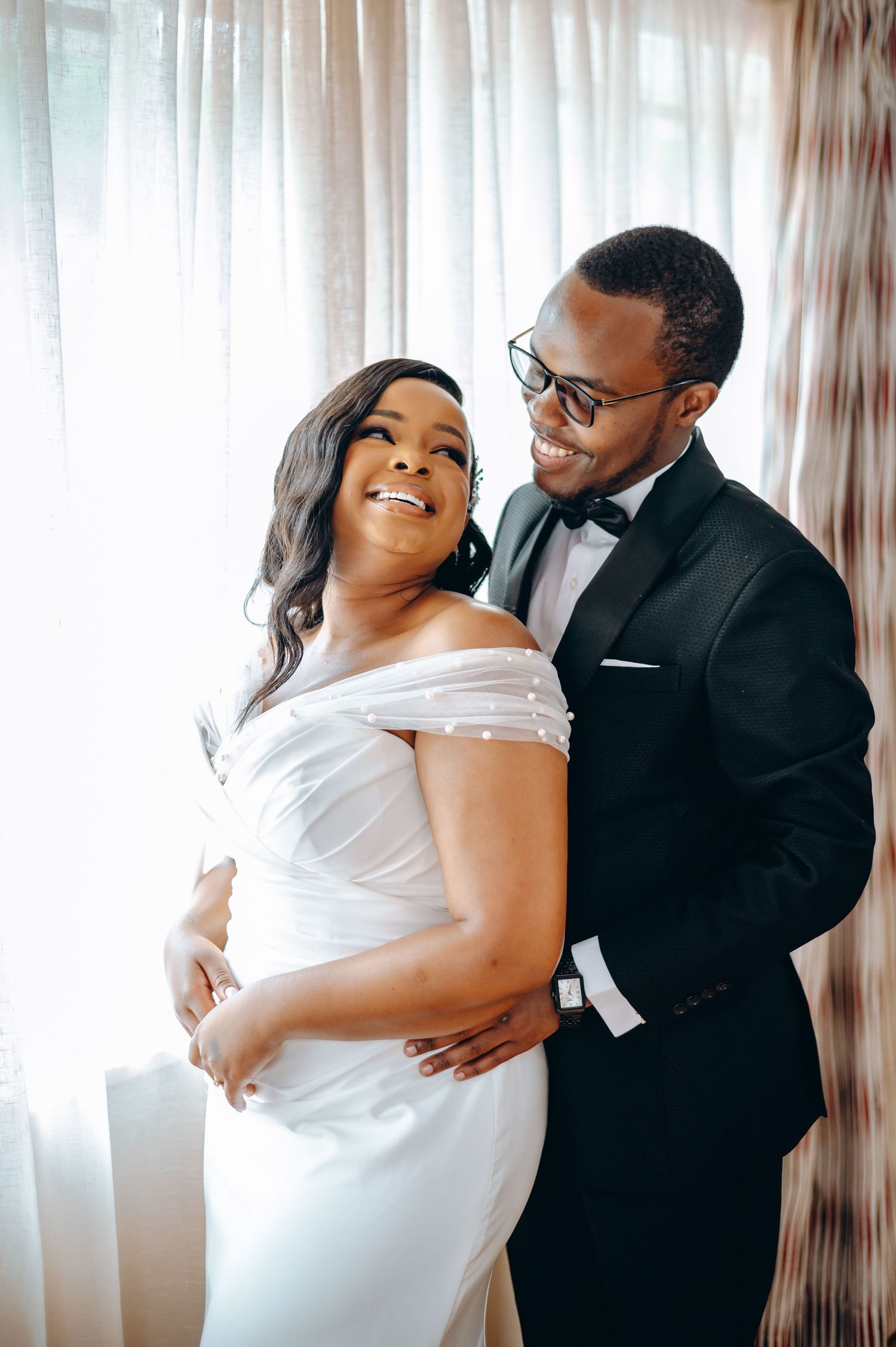Intimate indoor portrait of couple in classic black and white wedding attire.