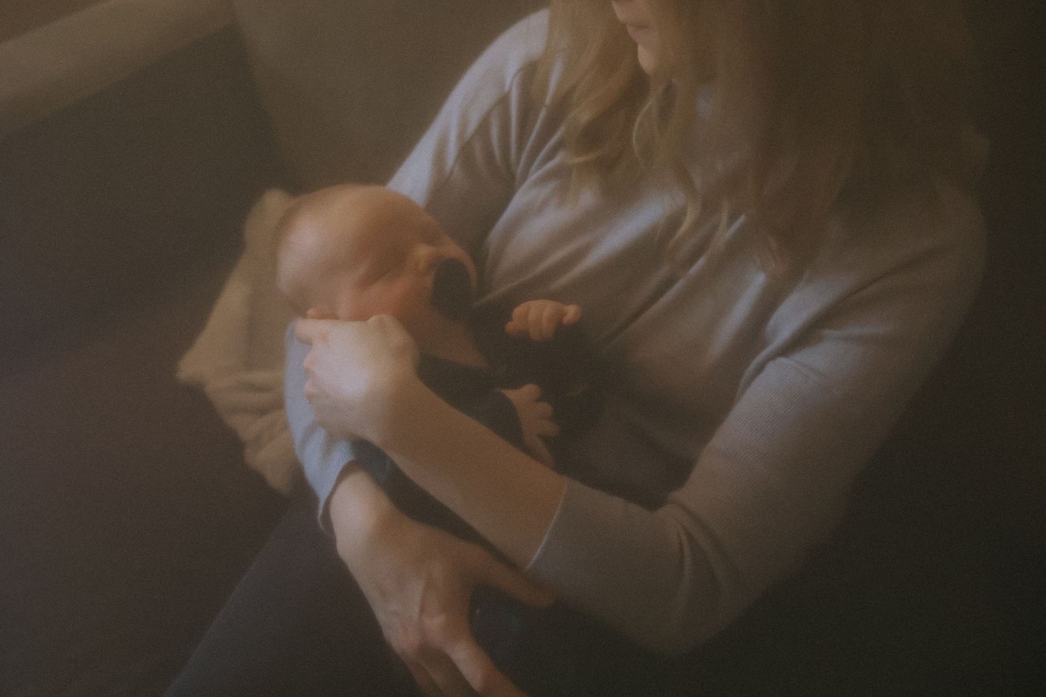 Mother tenderly cradling her newborn baby in a softly lit, intimate setting.