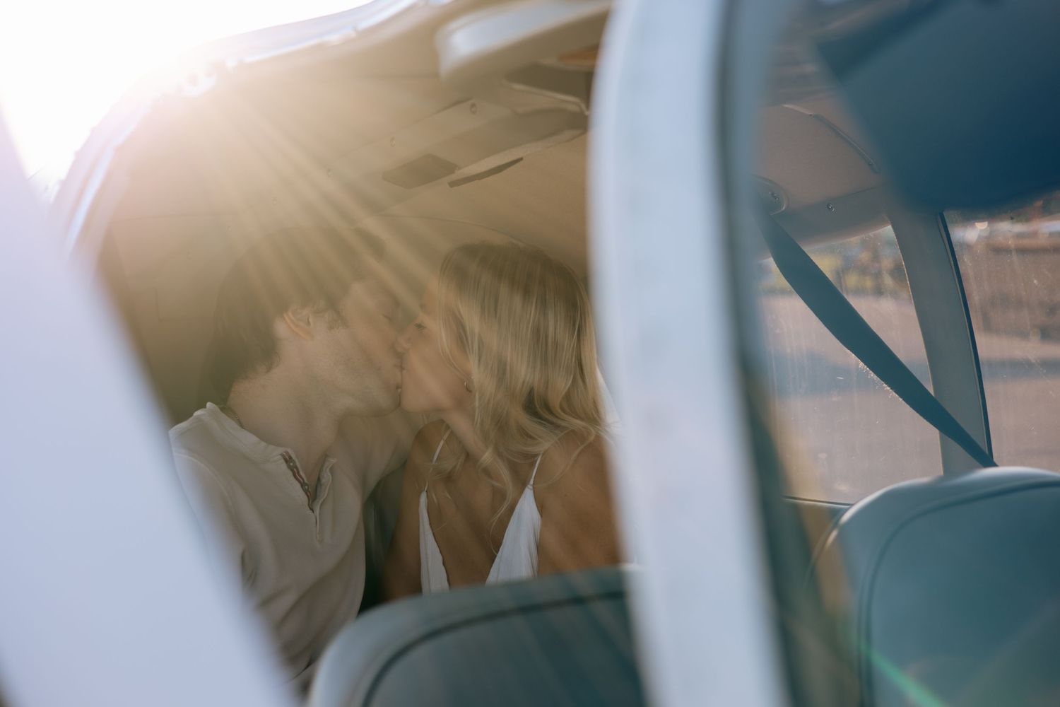 Couple sharing a romantic moment inside a small aircraft bathed in golden sunset light.