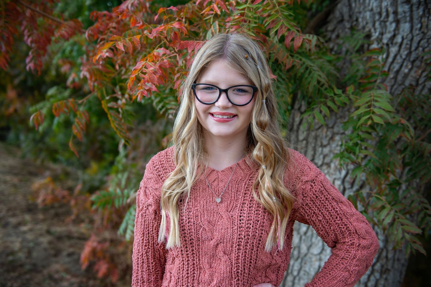 Portrait shot with autumn foliage background and warm orange tones.