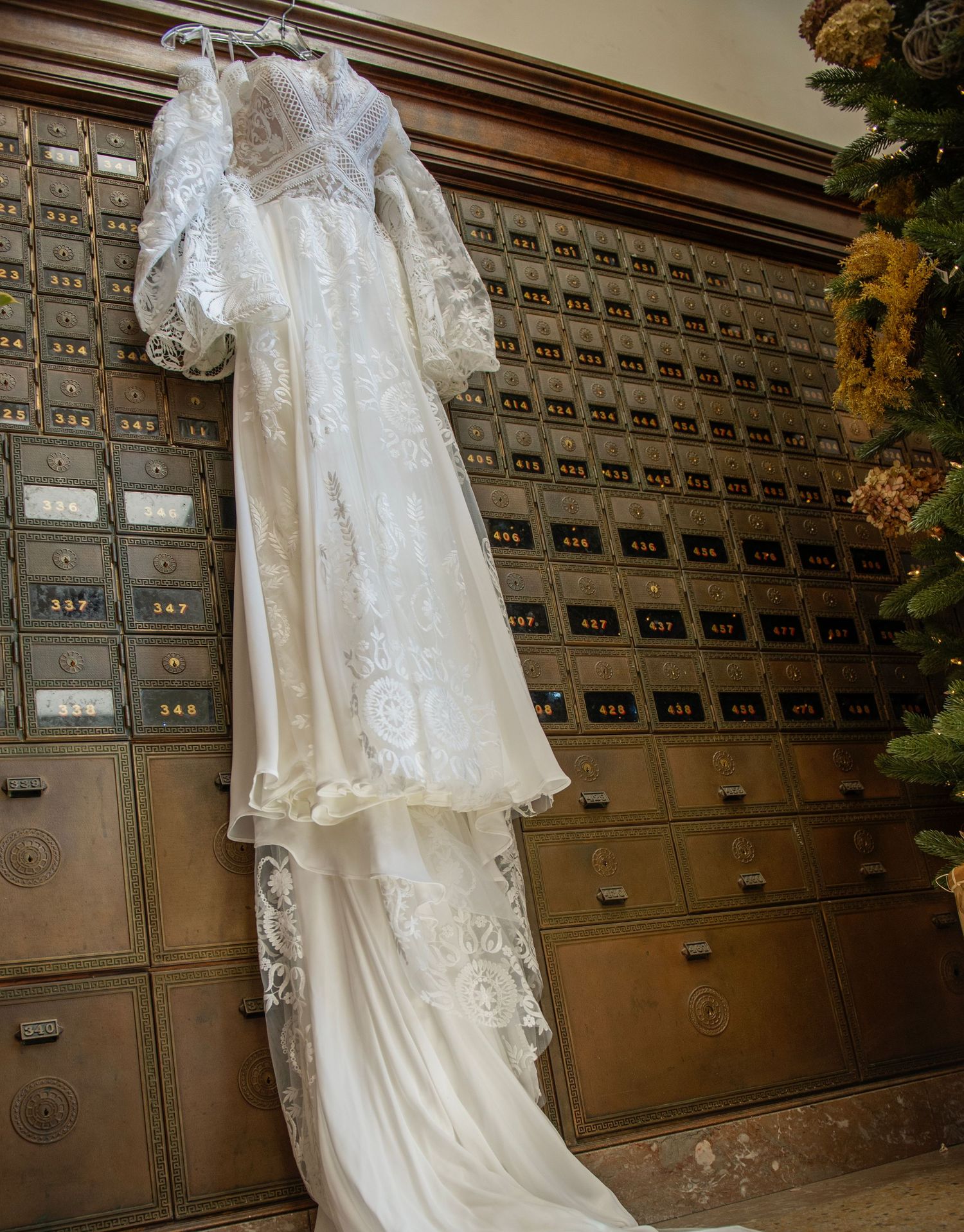 Elegant white lace wedding dress displayed against vintage mail lockers.