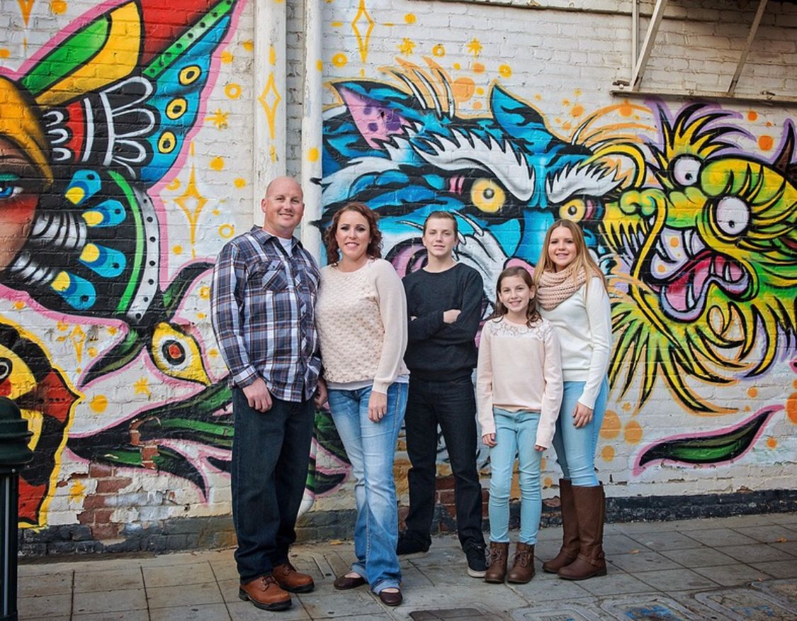 Family portrait session against colorful graffiti wall with butterfly artwork.