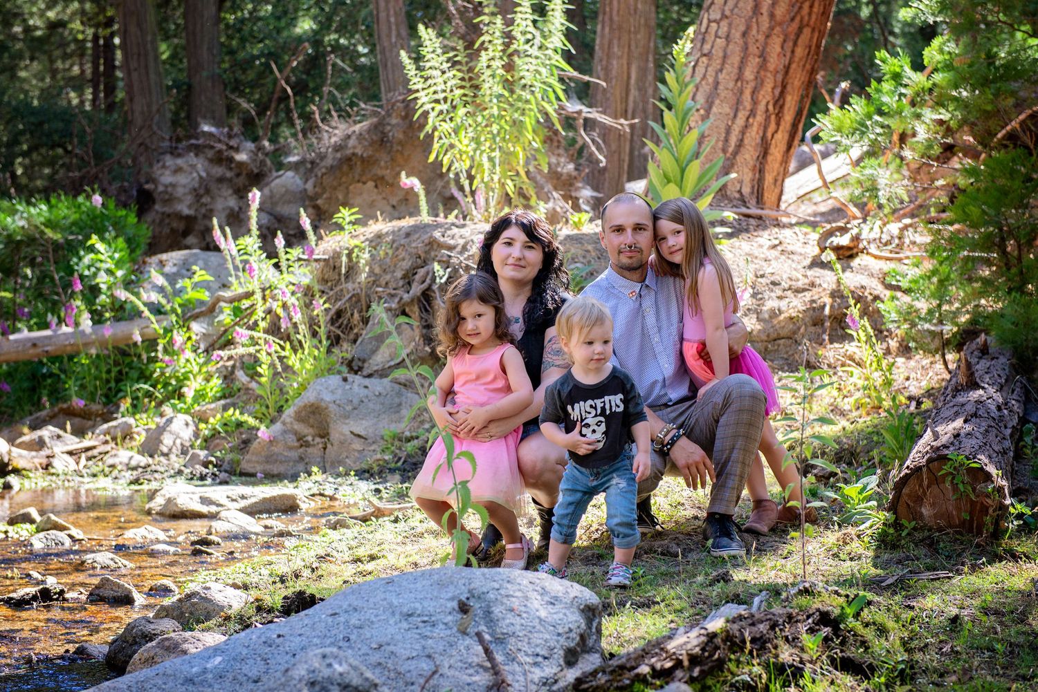 Children sitting together on garden rocks surrounded by lush greenery.