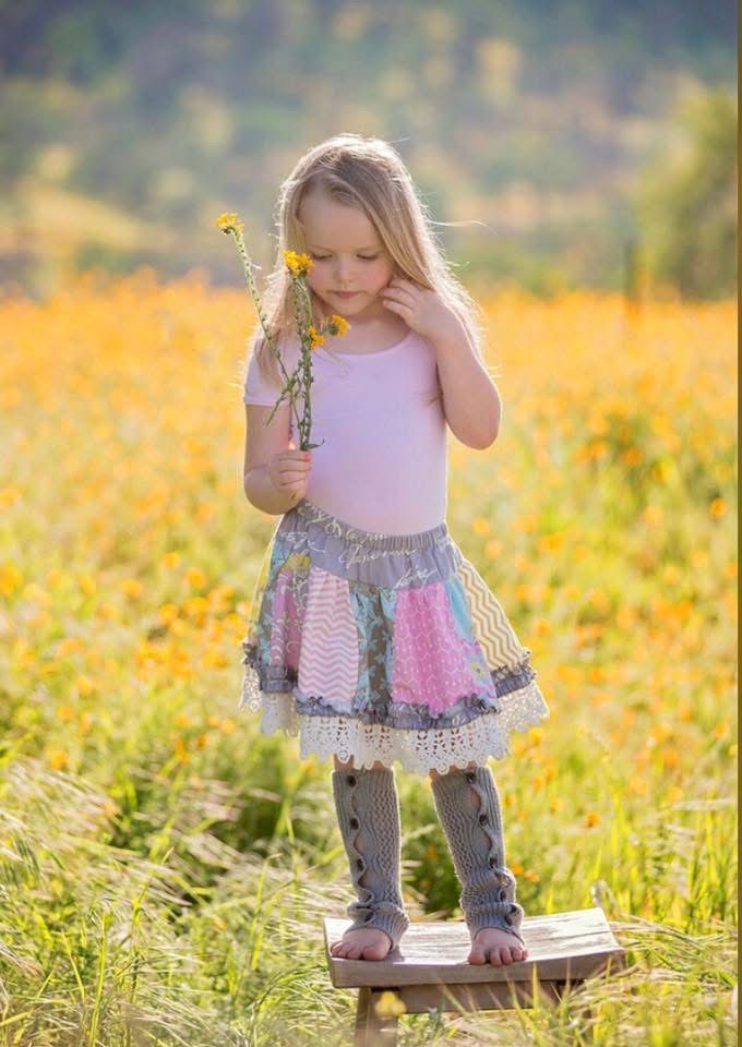 Young figure in pink tulle dress explores a sunlit field of wildflowers.
