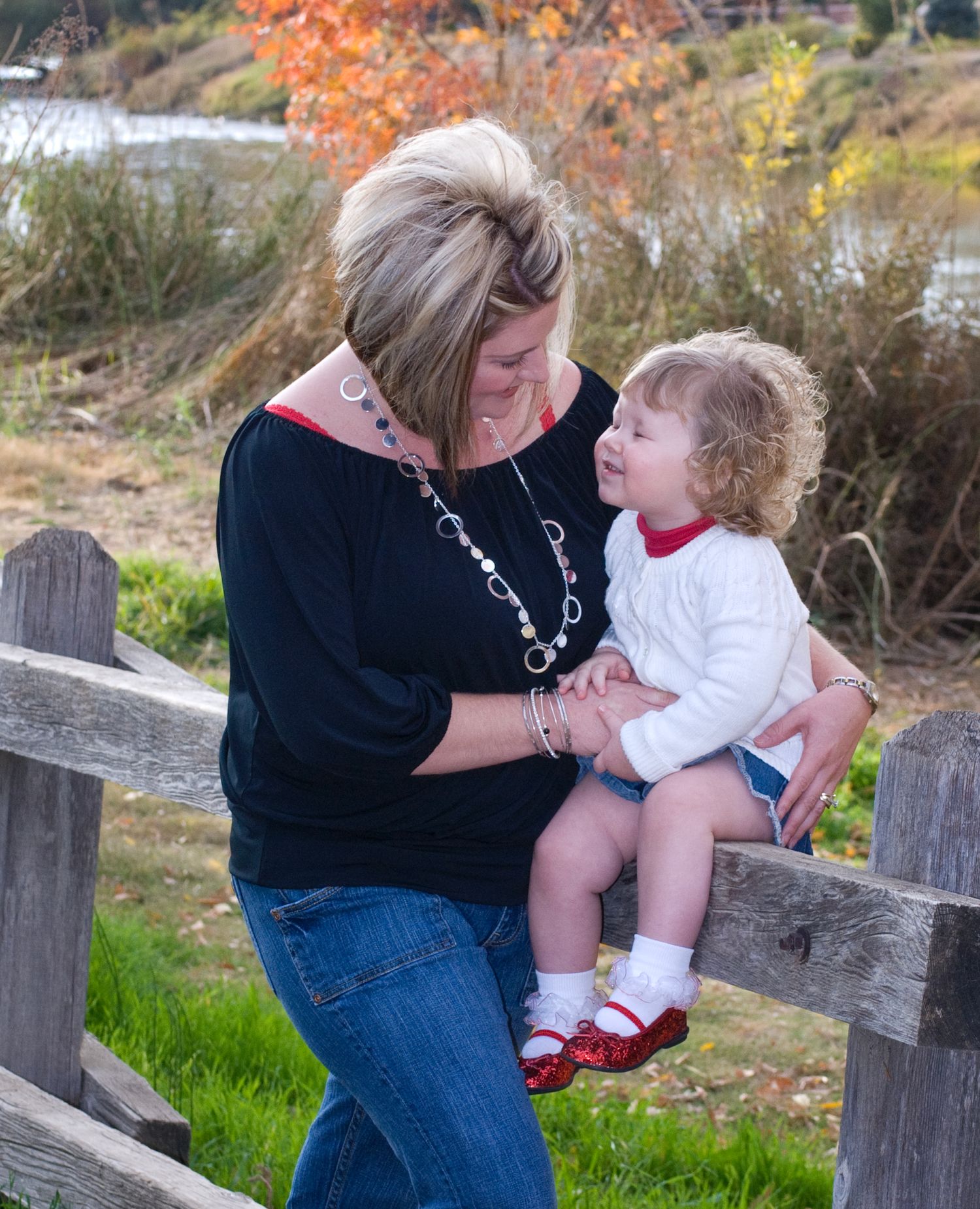 Sweet moments between adult and small child sitting together on wooden bench outdoors.