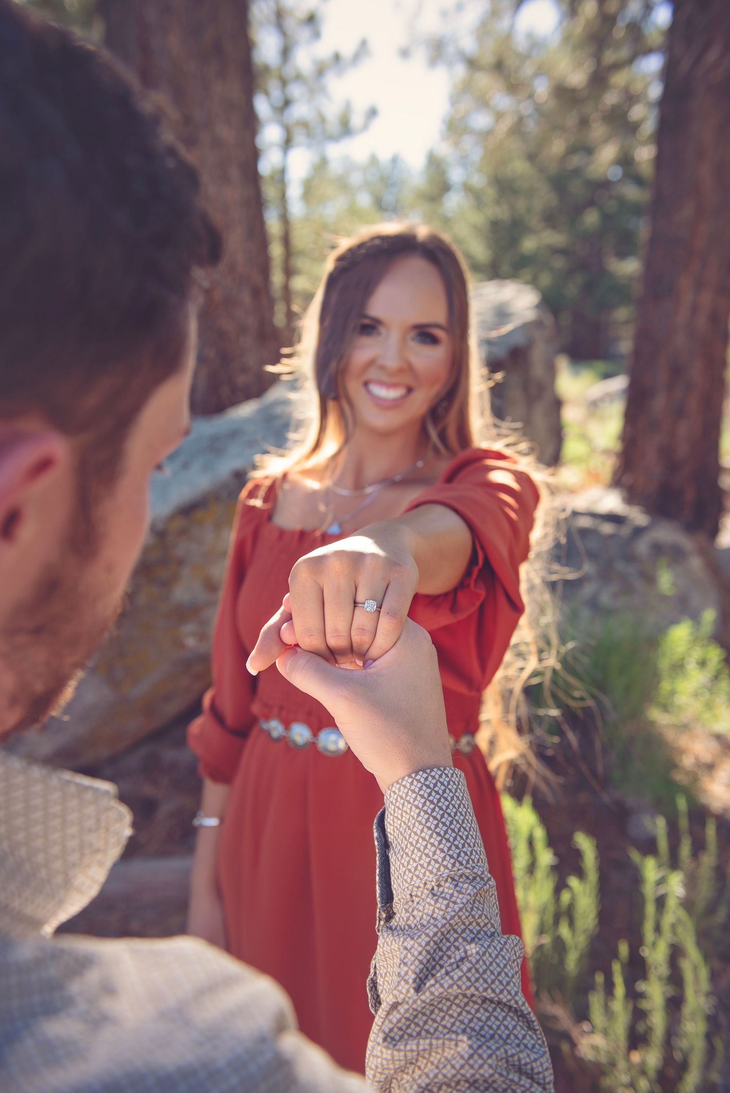 A joyful engagement photoshoot with playful moments between a couple in a forest setting.
