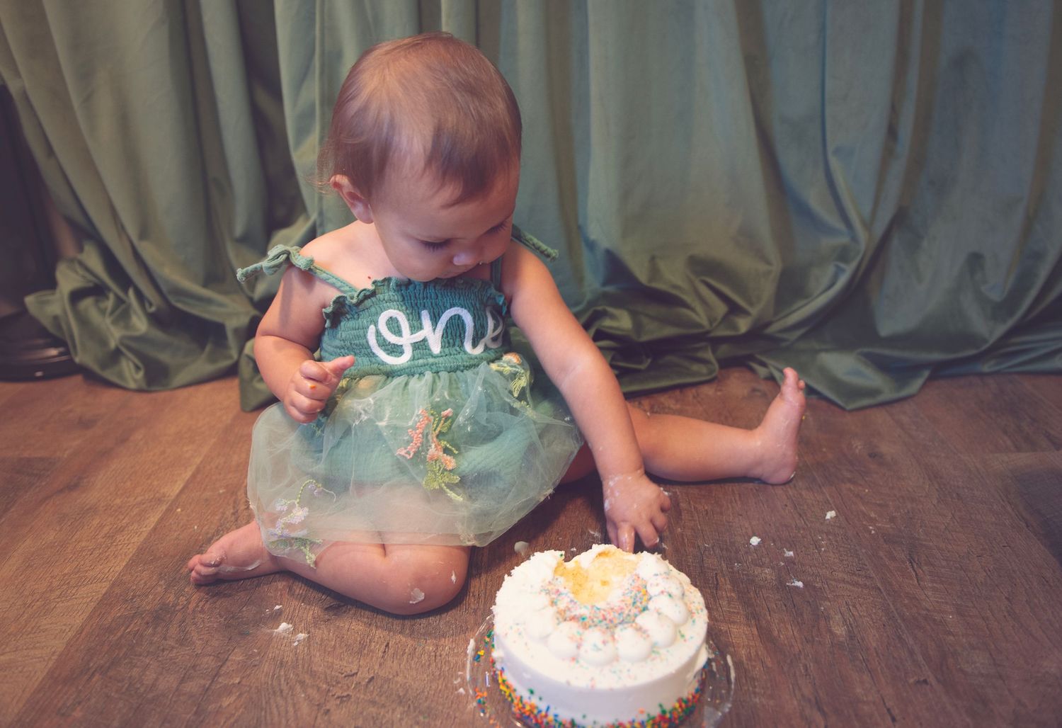 A sequence of photos capturing a cake smash celebration with a white frosted birthday cake.