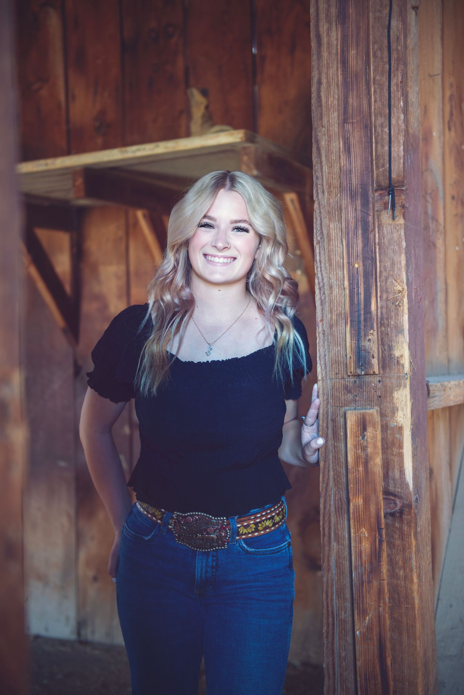 Rustic barn backdrop portrait session with casual jeans and black top outfit.