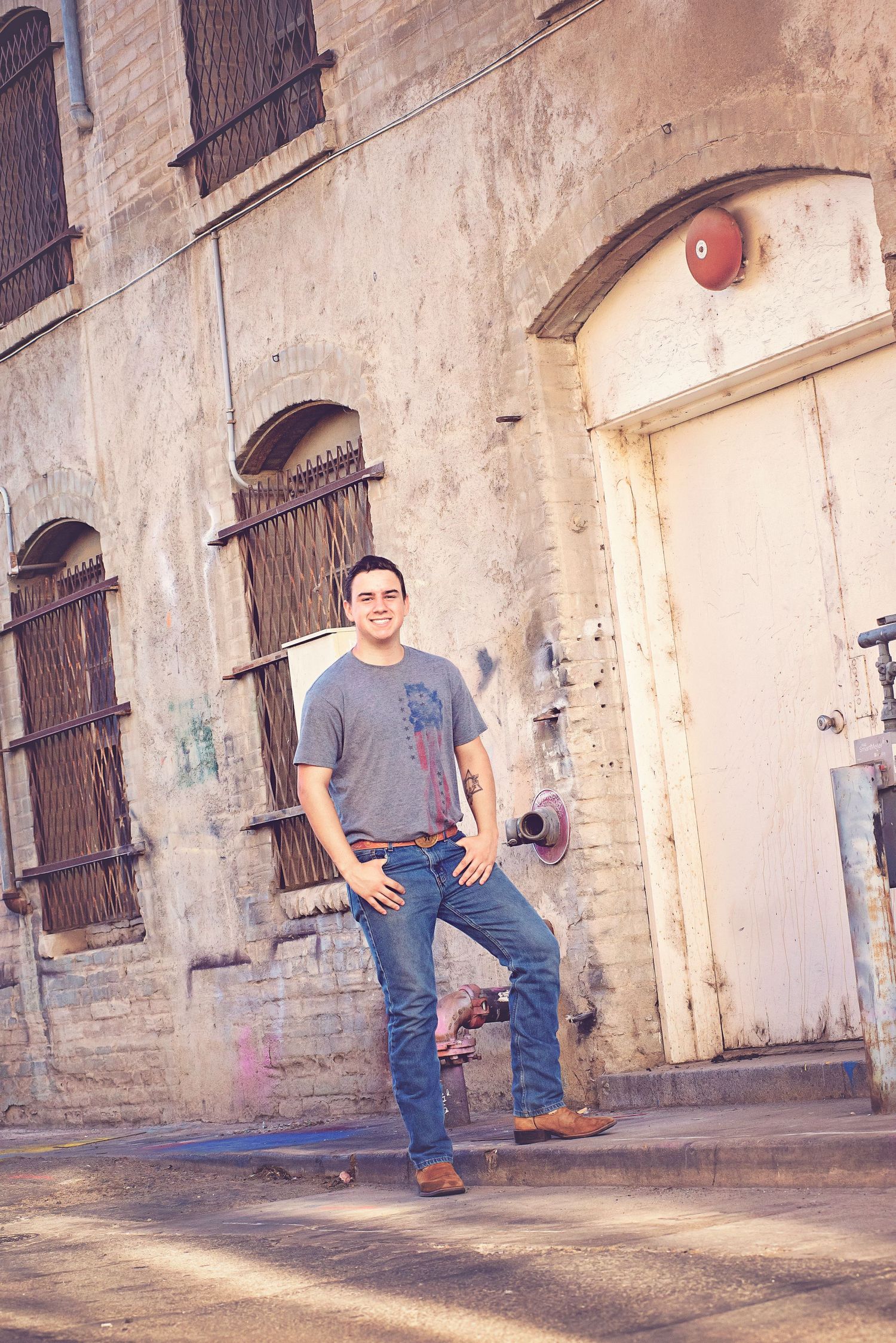 Urban photoshoot against weathered brick wall with barred windows.