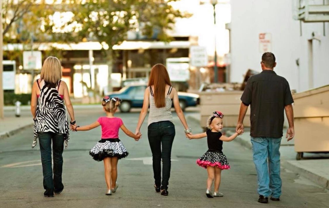 Silhouettes of family members walking together on a path at sunset.