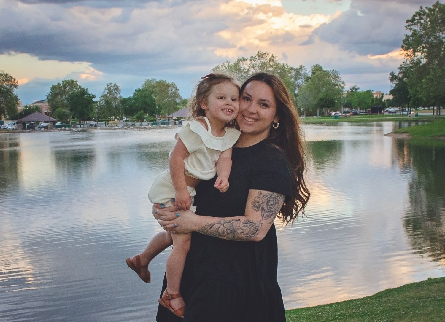 Sunset family photoshoot by a serene lake with warm golden lighting.