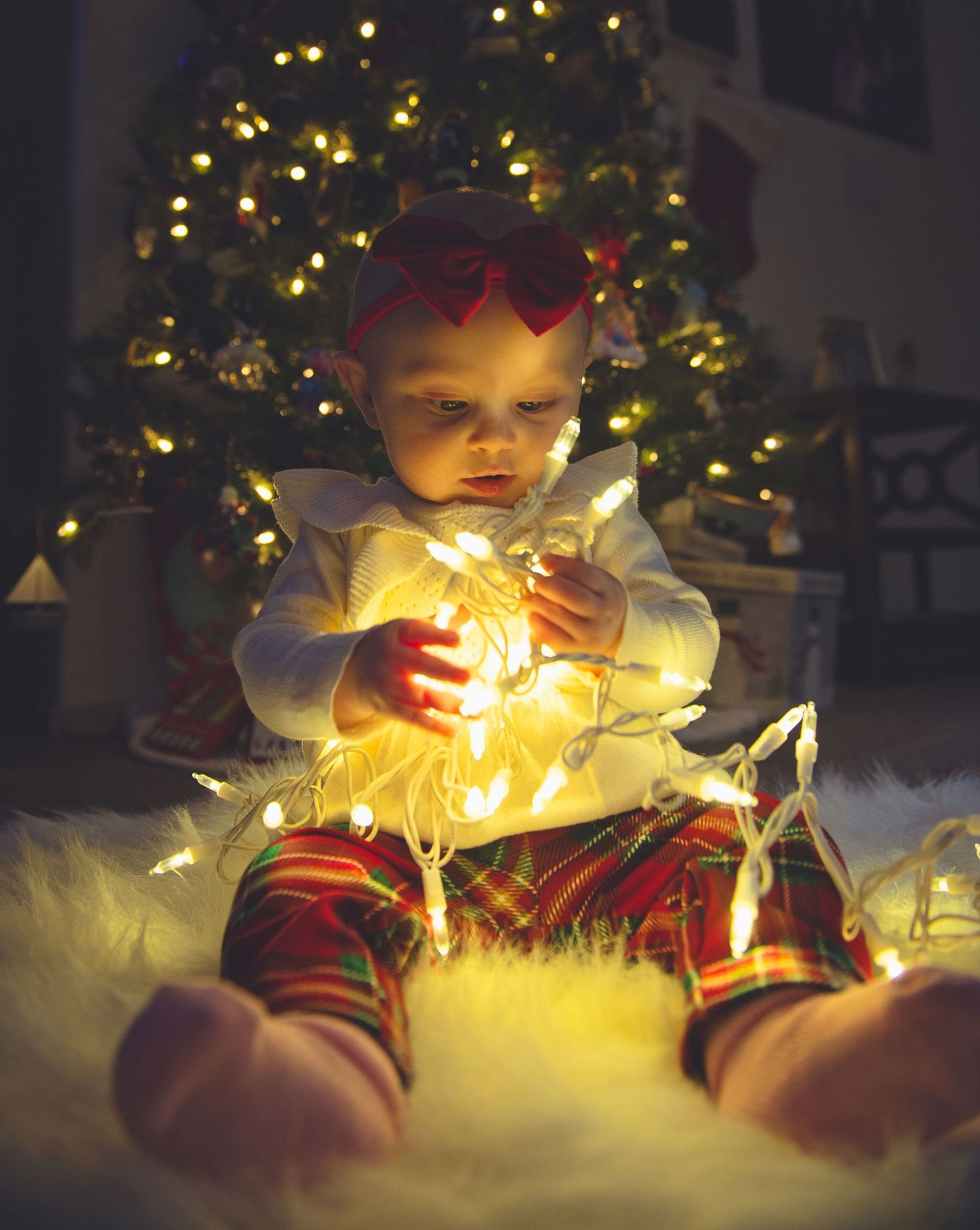Child playing with glowing string lights creating a magical holiday atmosphere against dark background.