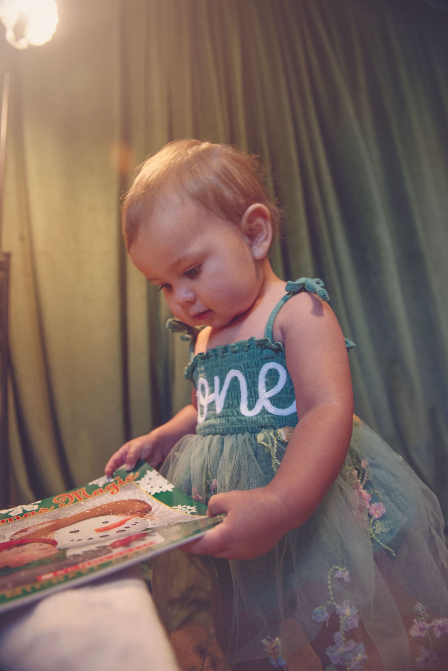A sequence showing a toddler in a teal dress examining a decorated birthday cake.