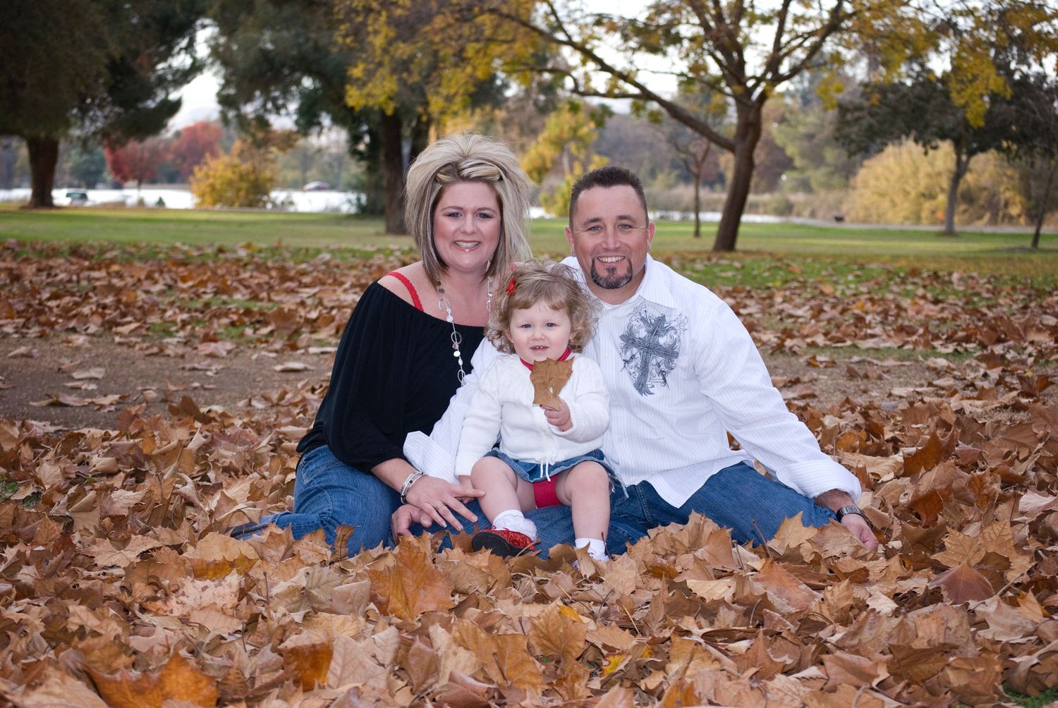 Family laying in autumn leaves during outdoor photo session.