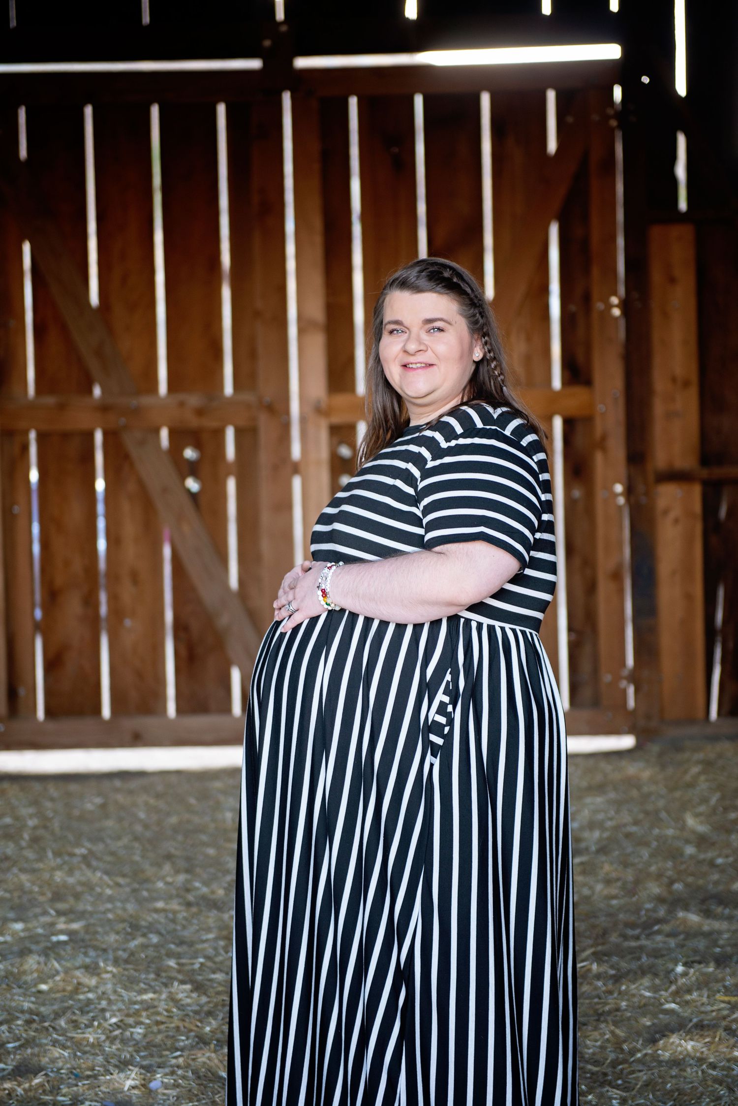 Portrait in rustic barn wearing black and white striped dress. Maternity