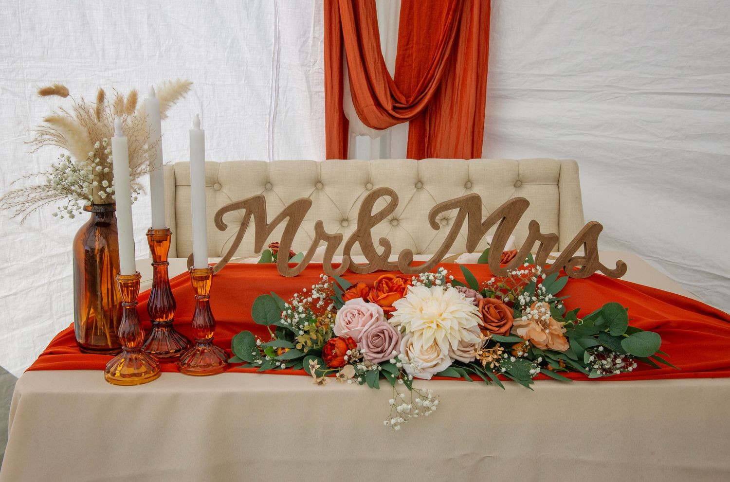 Wedding reception table decor with red tablecloth and Mr & Mrs sign with rustic elements.