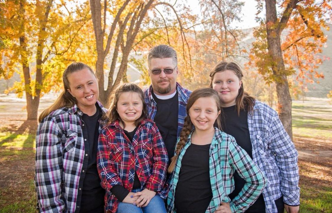 Large family group poses together among autumn trees with golden foliage.