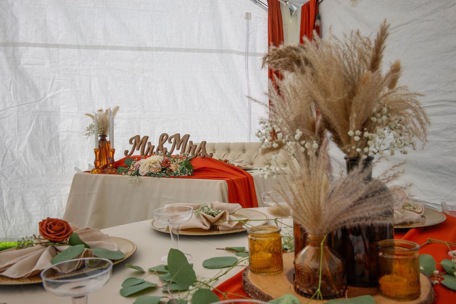 Elegant wedding table setting with pampas grass, rust-colored linens, and dried floral arrangements.
