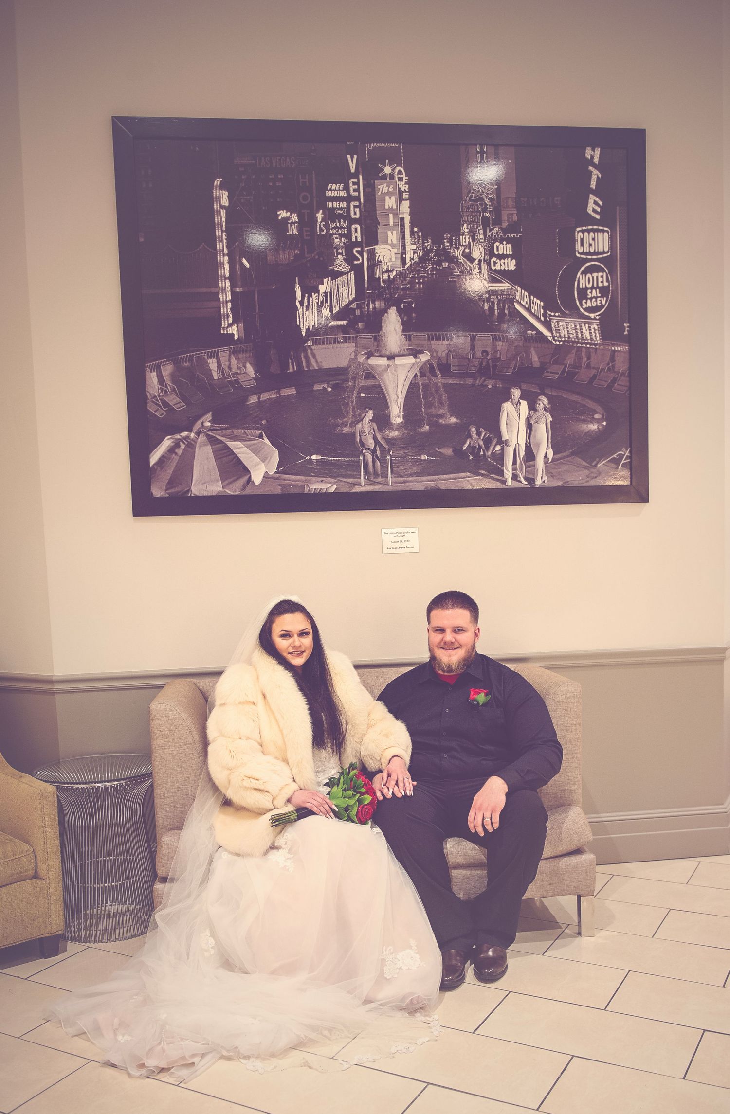 Couple poses near vintage black and white movie scene photographs in gallery.