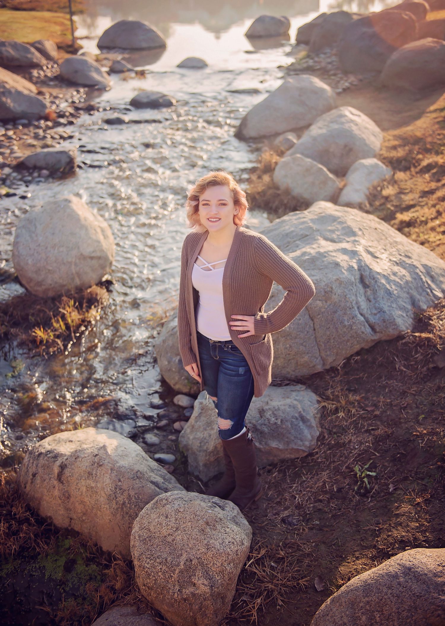 Child climbing on coastal rocks during golden hour sunset.