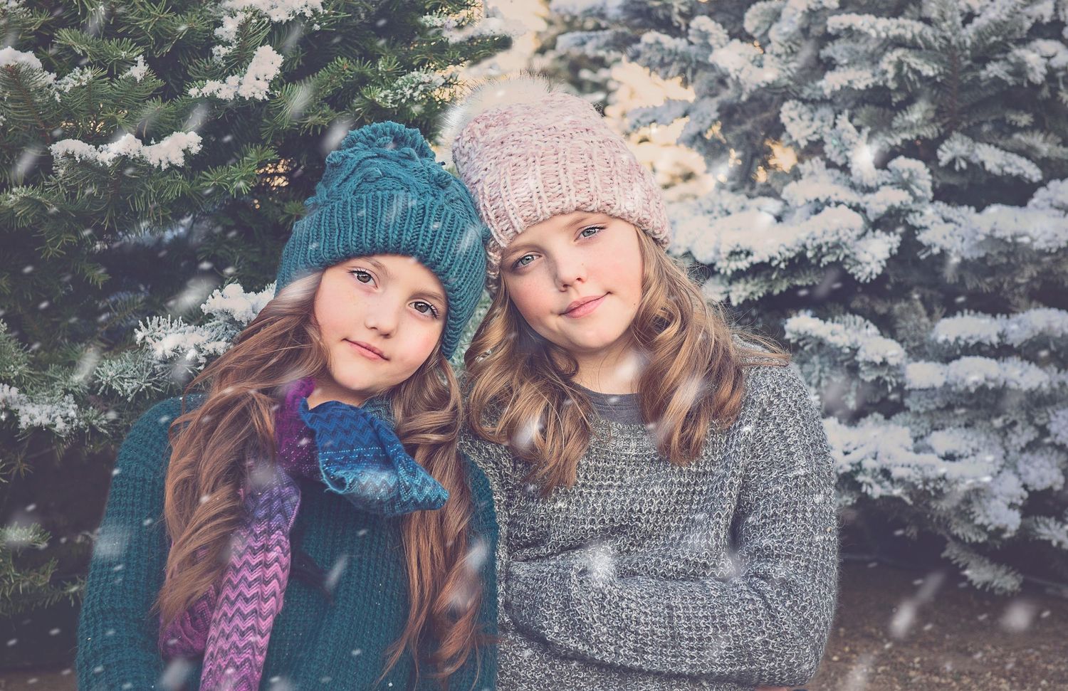 Friends wearing winter knit accessories pose together in snowy outdoor setting.