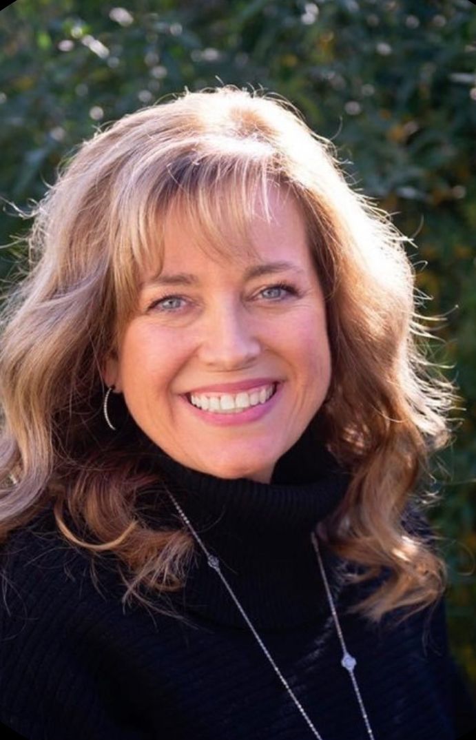 Close-up portrait of someone wearing black turtleneck against blurred natural background.