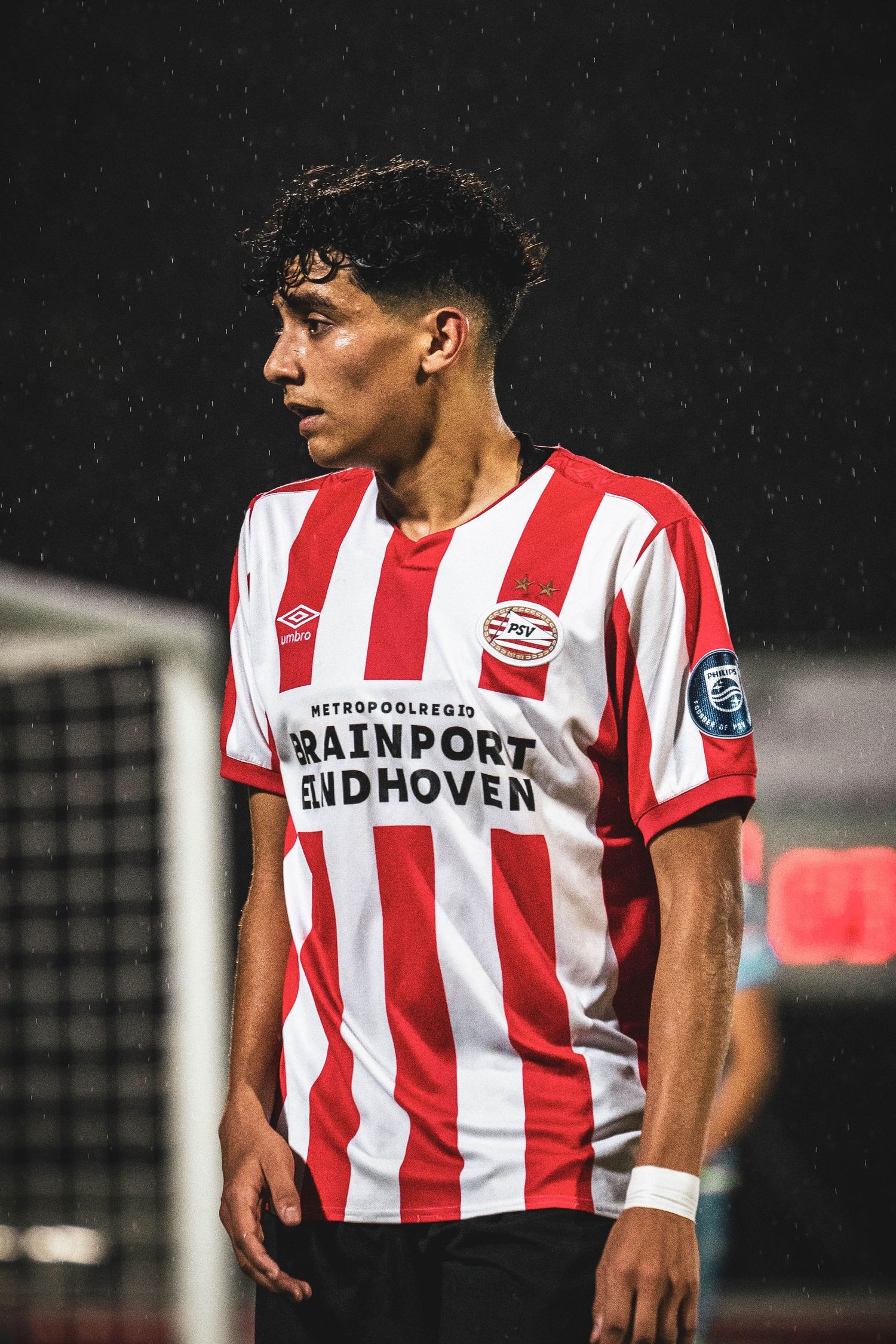 PSV Eindhoven player in iconic red and white striped jersey during rainy match.