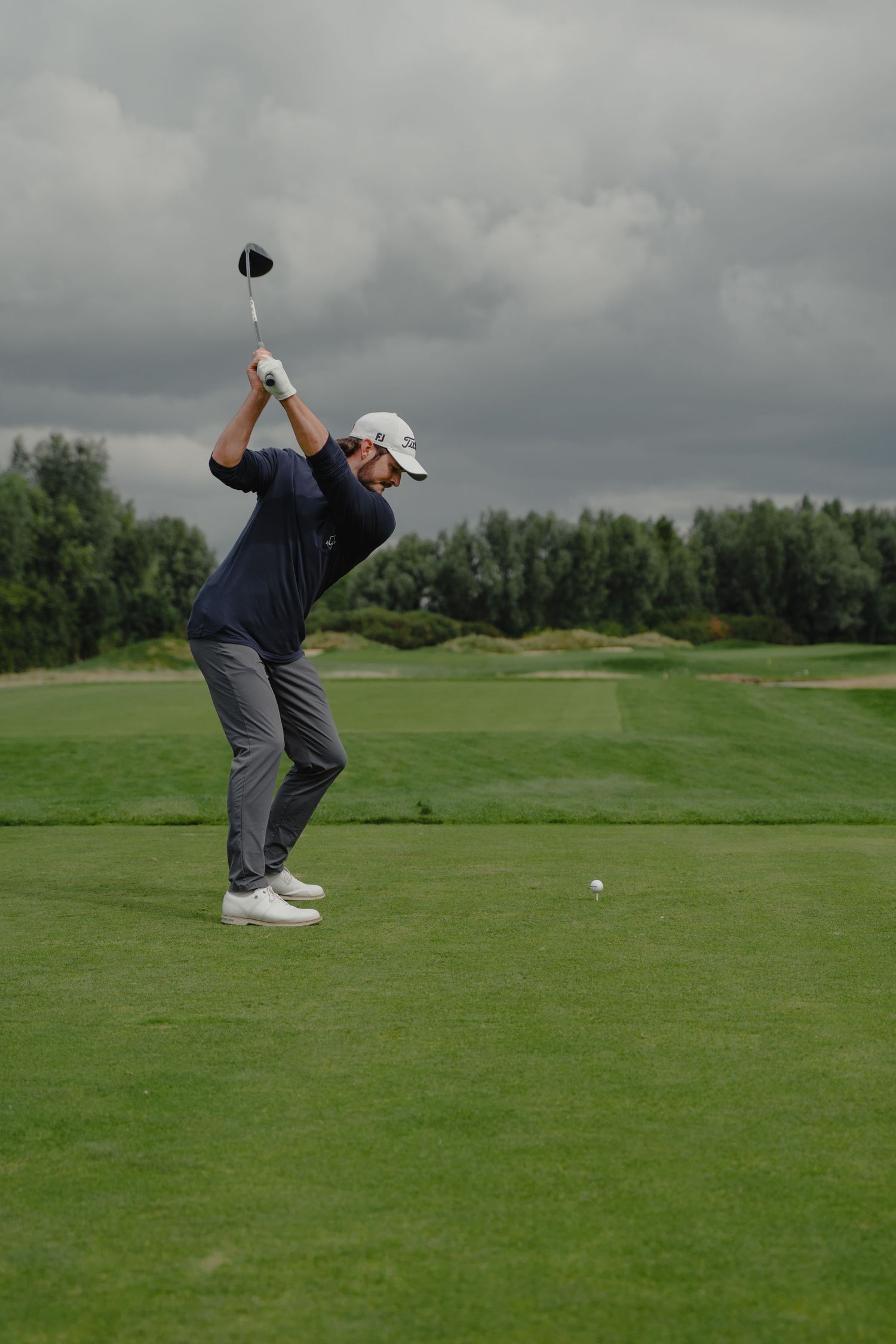 Sequence of golf swing motion shots on a cloudy day at a green golf course.