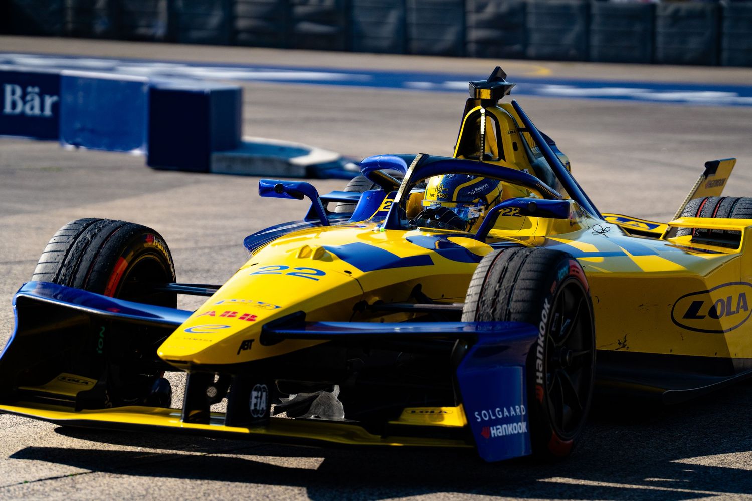 Yellow and blue Formula E electric racing car speeding on a street circuit track during a competitive race.