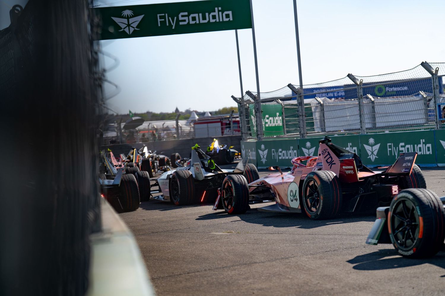 Formula E race cars competing on track with FlySaudia sponsorship banners visible in the background.