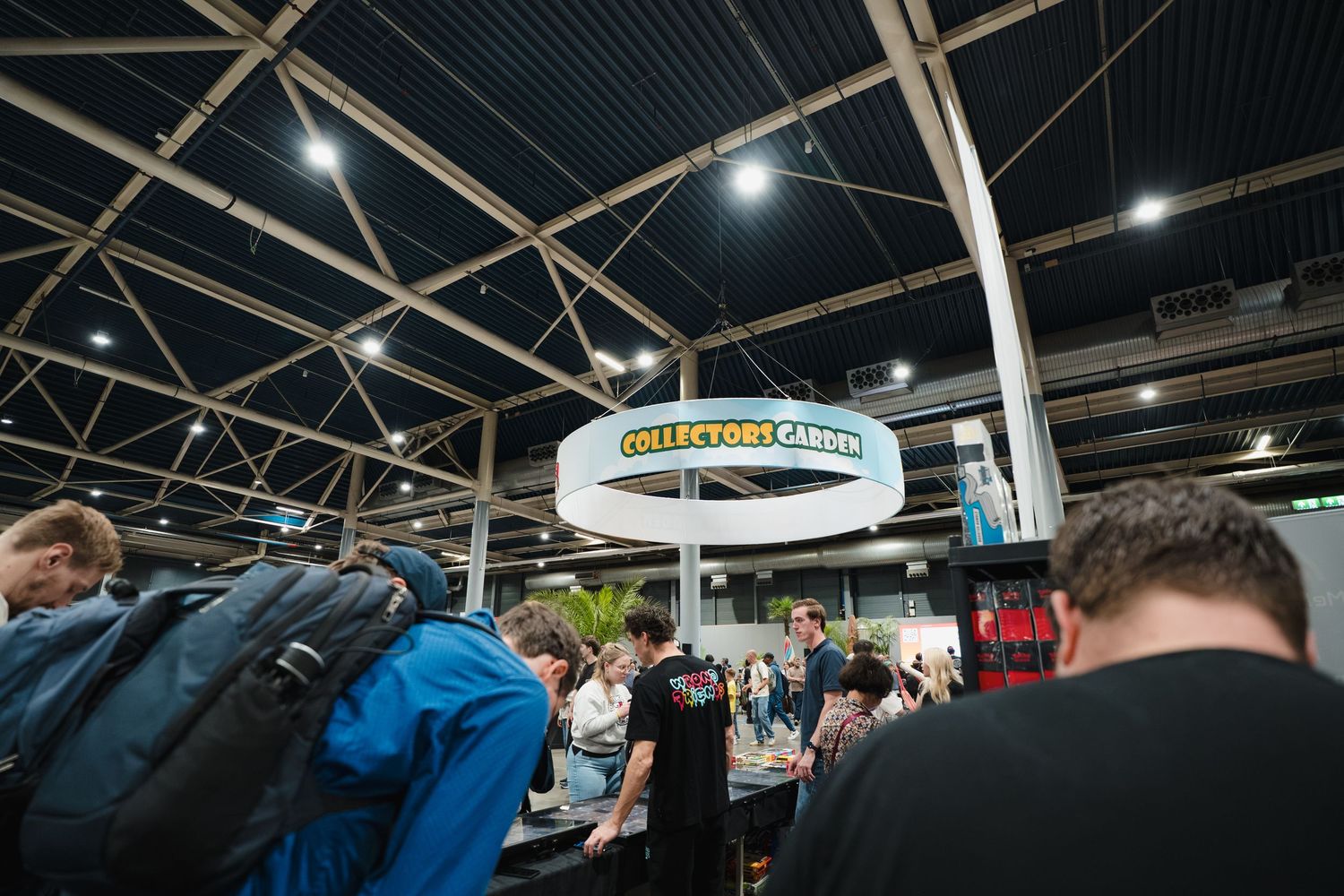 Crowded Collectors Corner booth at a convention center with circular signage and bright overhead lighting.