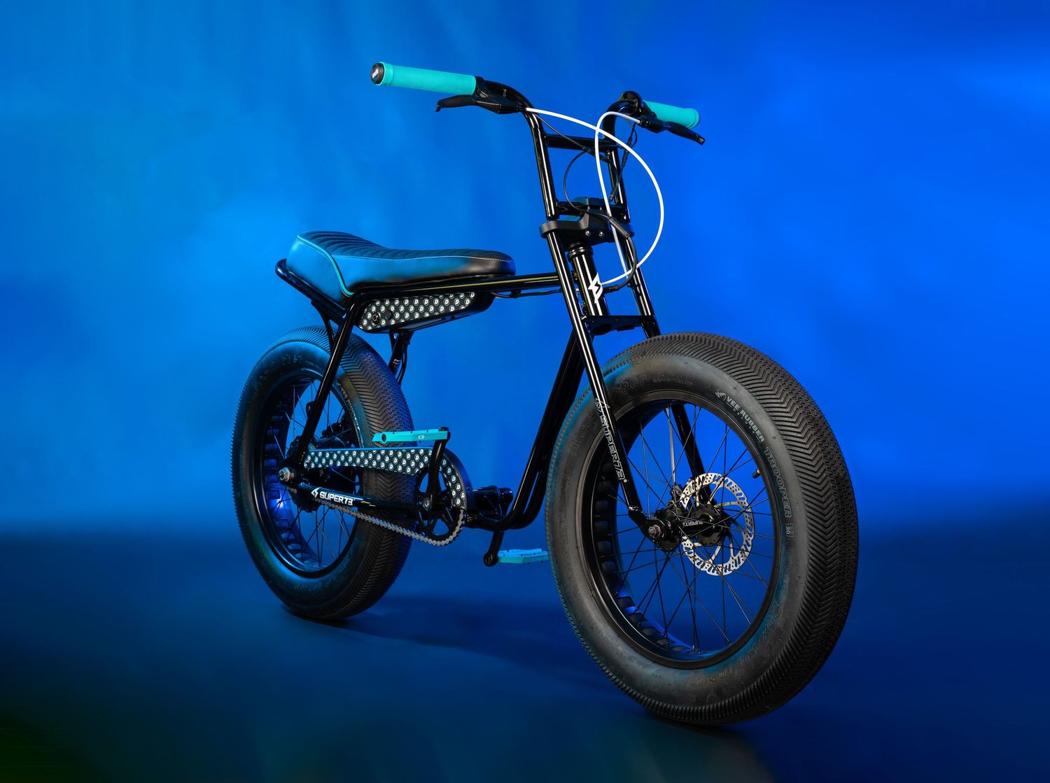 Modern electric bicycle with fat tires and blue accents photographed against blue background.