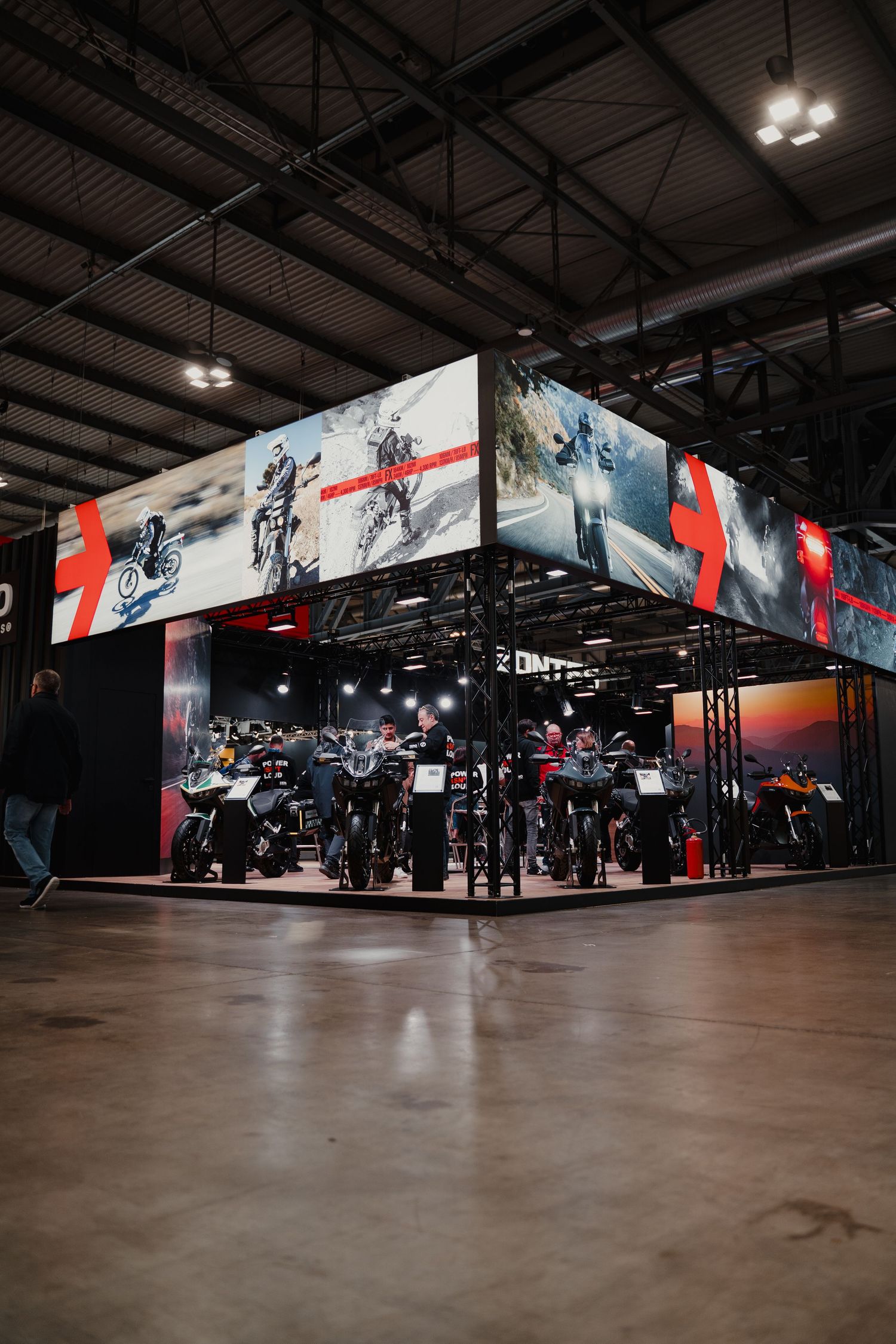 Motorcycle showroom display with dramatic lighting and large action sports photography.