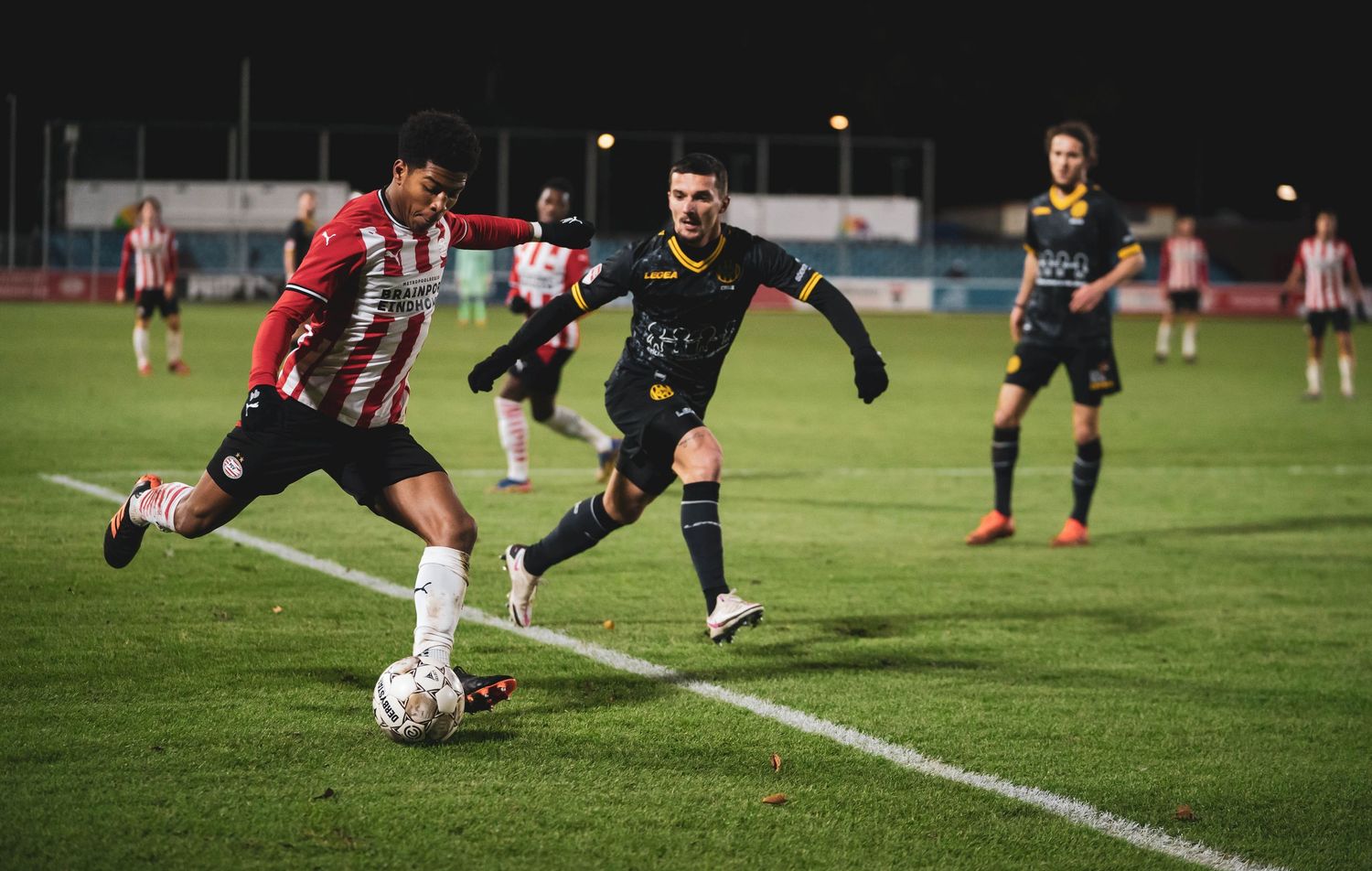 Soccer action shot showing players challenging for the ball near the sideline.