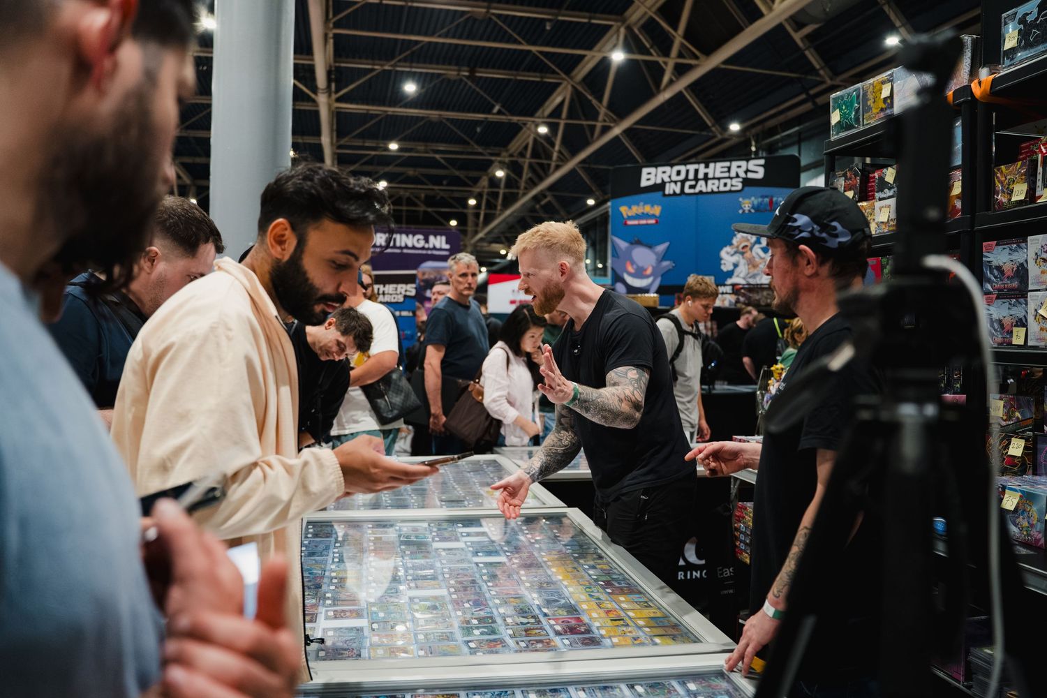 Customers browsing trading cards at Brothers in Cards convention booth with glass display cases.