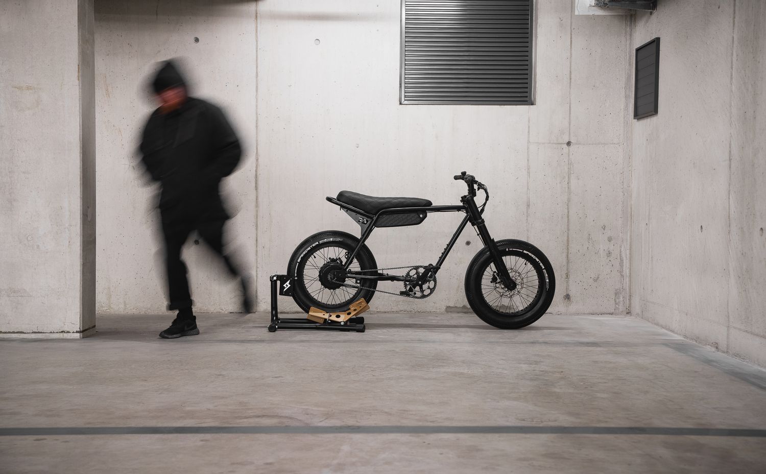 Black and white image of motorcycles in minimalist concrete parking garage.