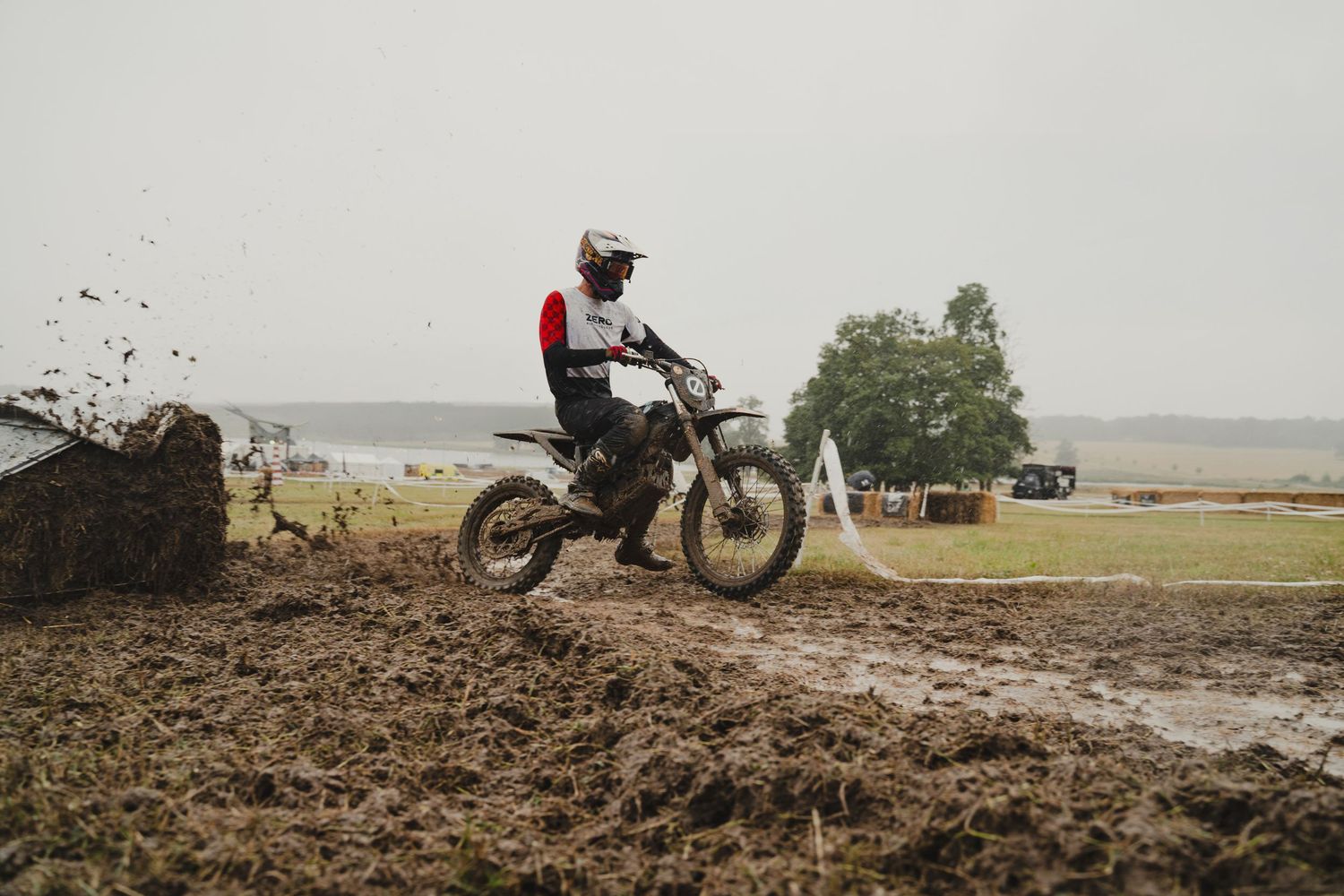 Dirt bike rider splashing through muddy terrain during an off-road race.